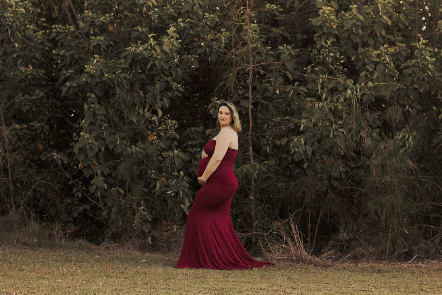 Pregnant mother standing in a golden field during sunset maternity photography session in Hervey Bay.