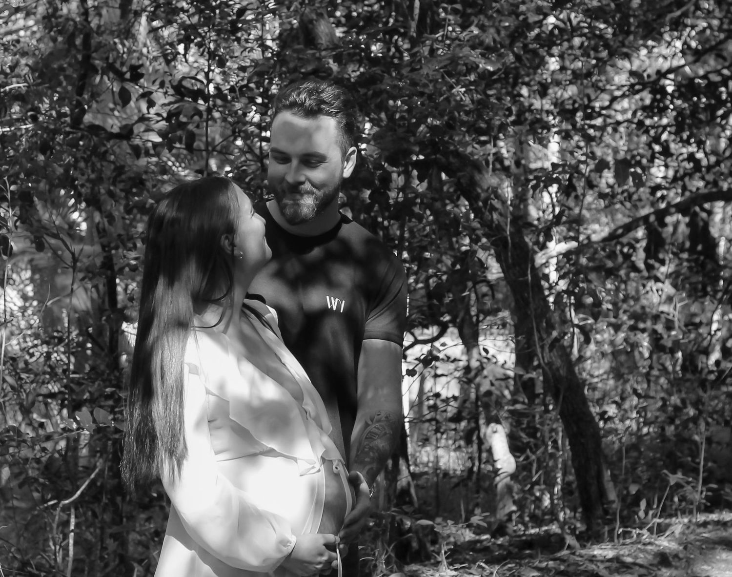 Mother to be and Father to be cuddling their first baby bump during a relaxed outdoor motherhood photography session in Hervey Bay.