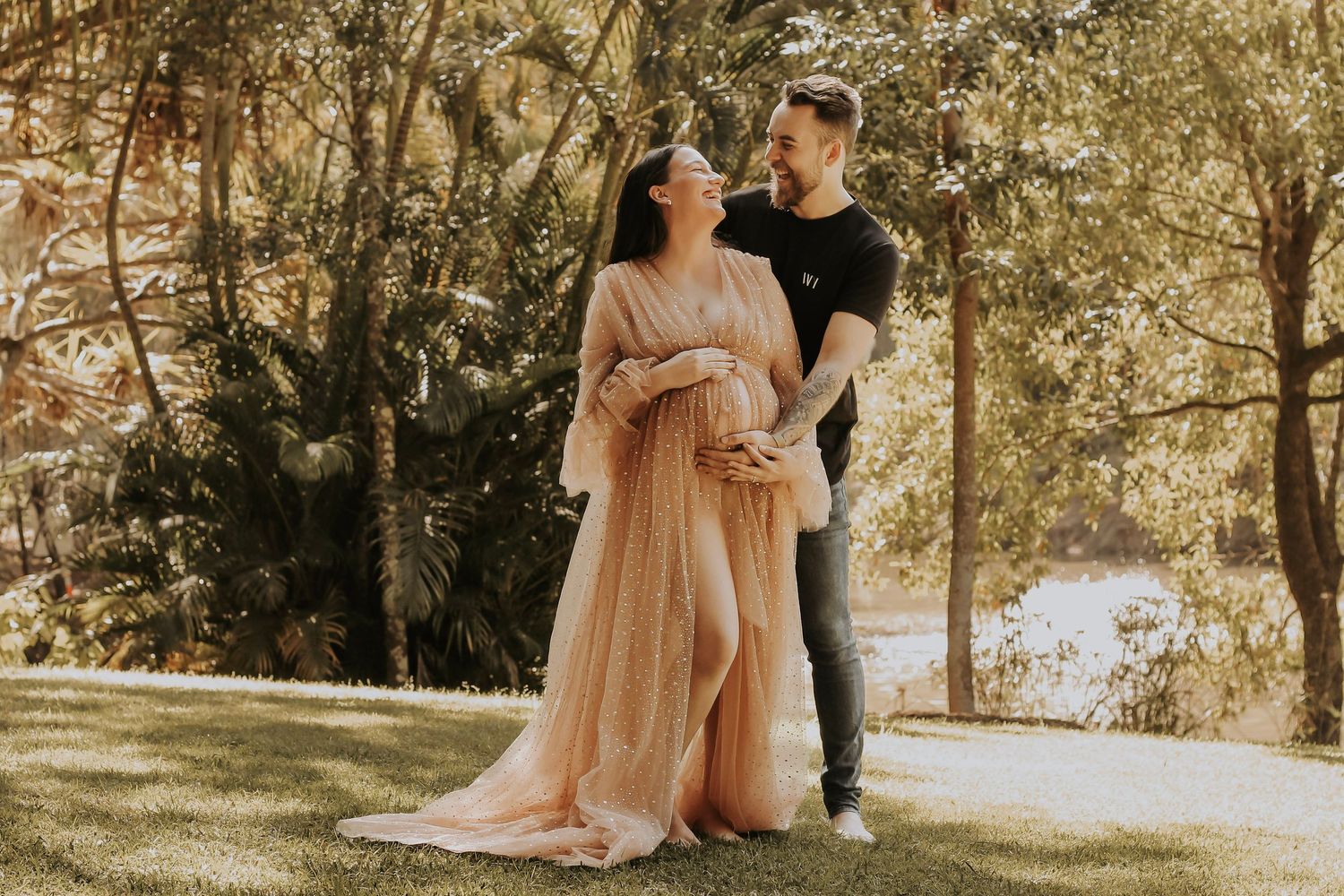 Mother to be and Father to be cuddling their first baby bump during a relaxed outdoor motherhood photography session in Hervey Bay.