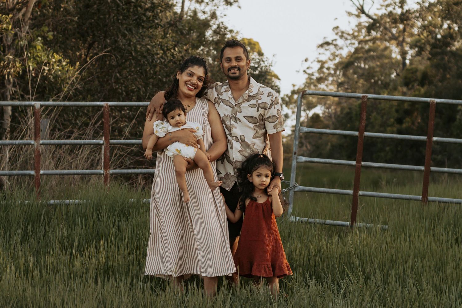 Beautiful family four in a field during a sunset family photography session in Hervey Bay.