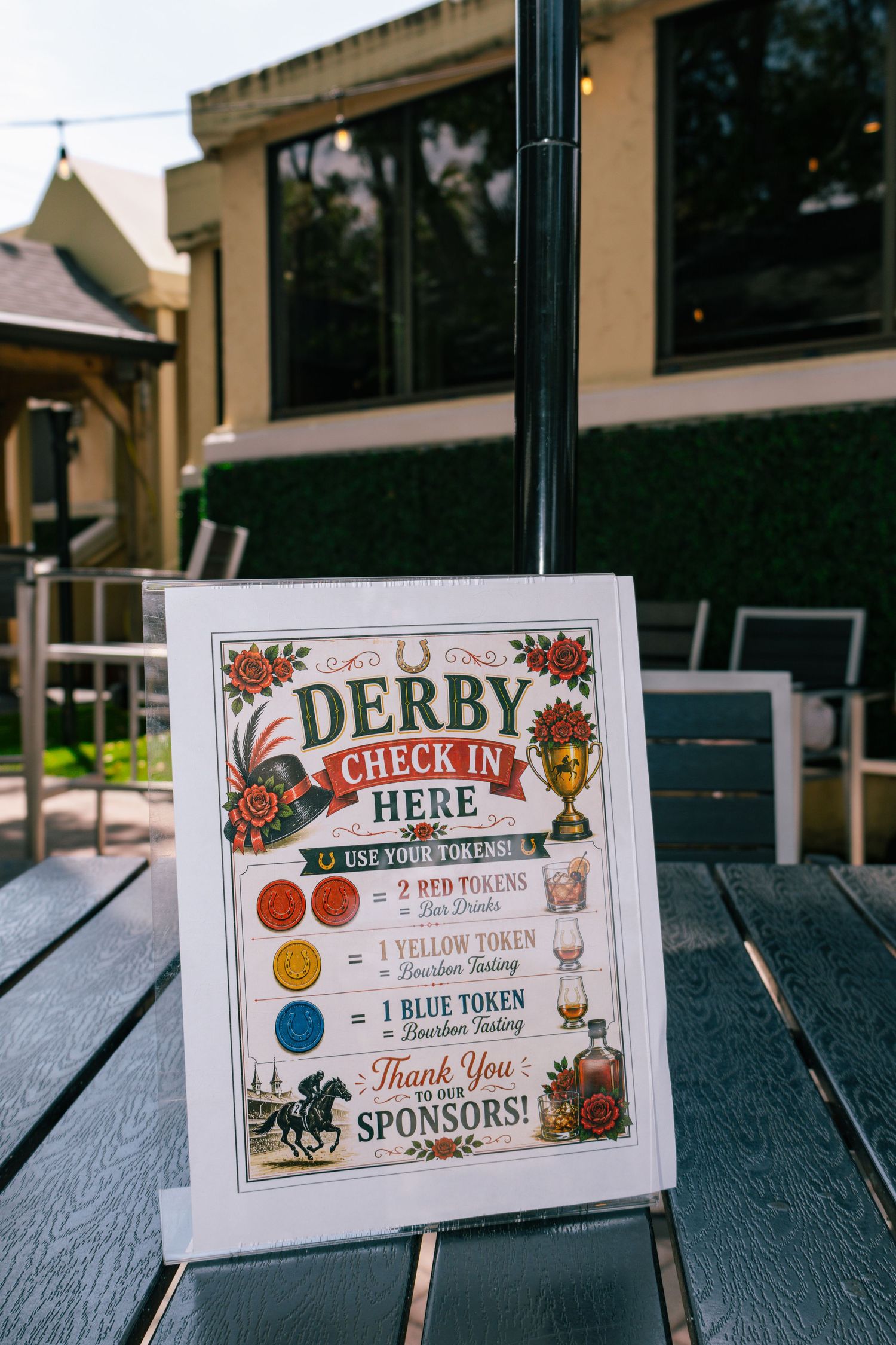 Kentucky Derby check-in sign with colorful token system and sponsor thank you message displayed outdoors.