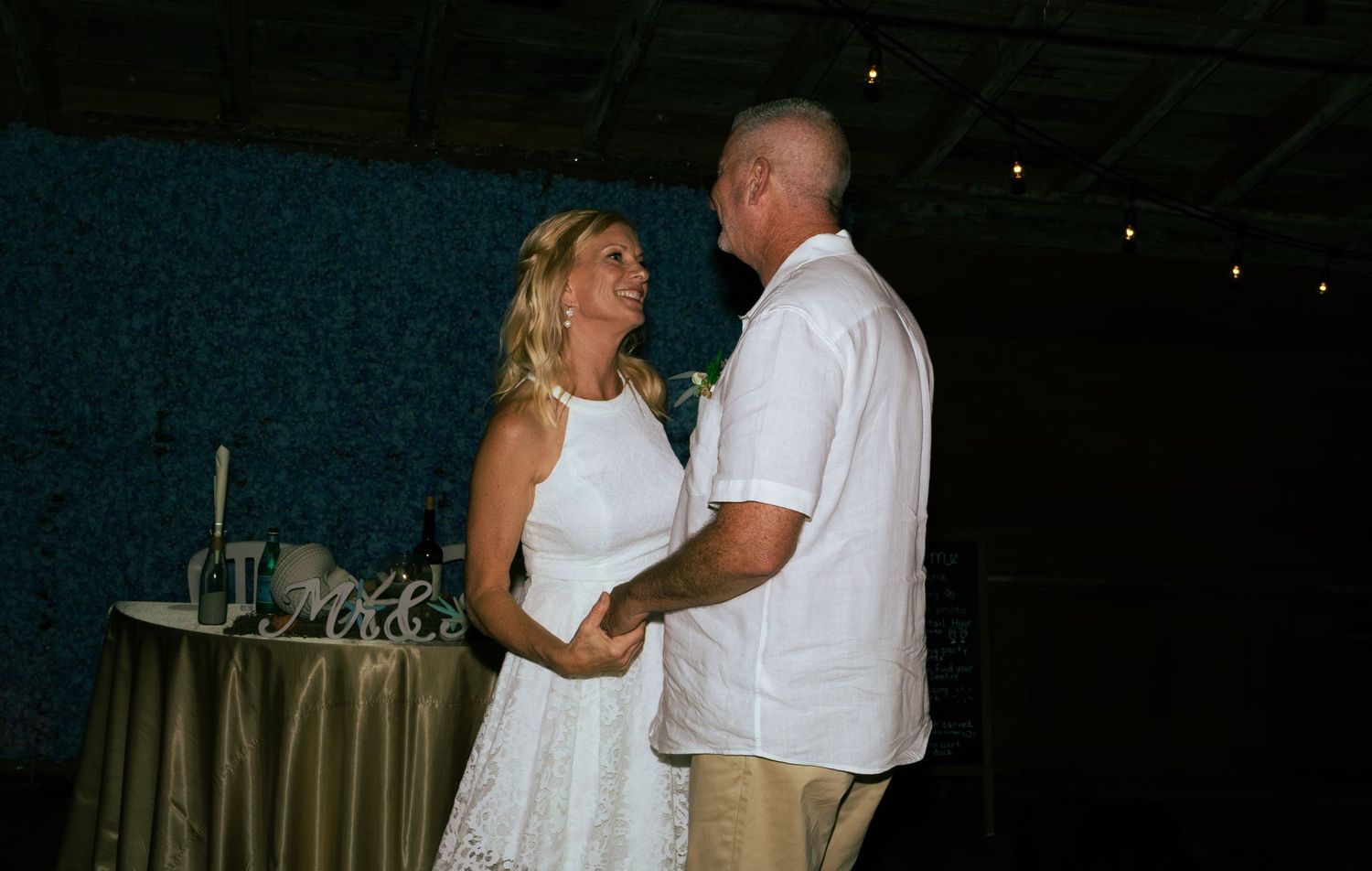 Bride and groom share a tender first dance at their wedding reception with Mr and Mrs sign in background.