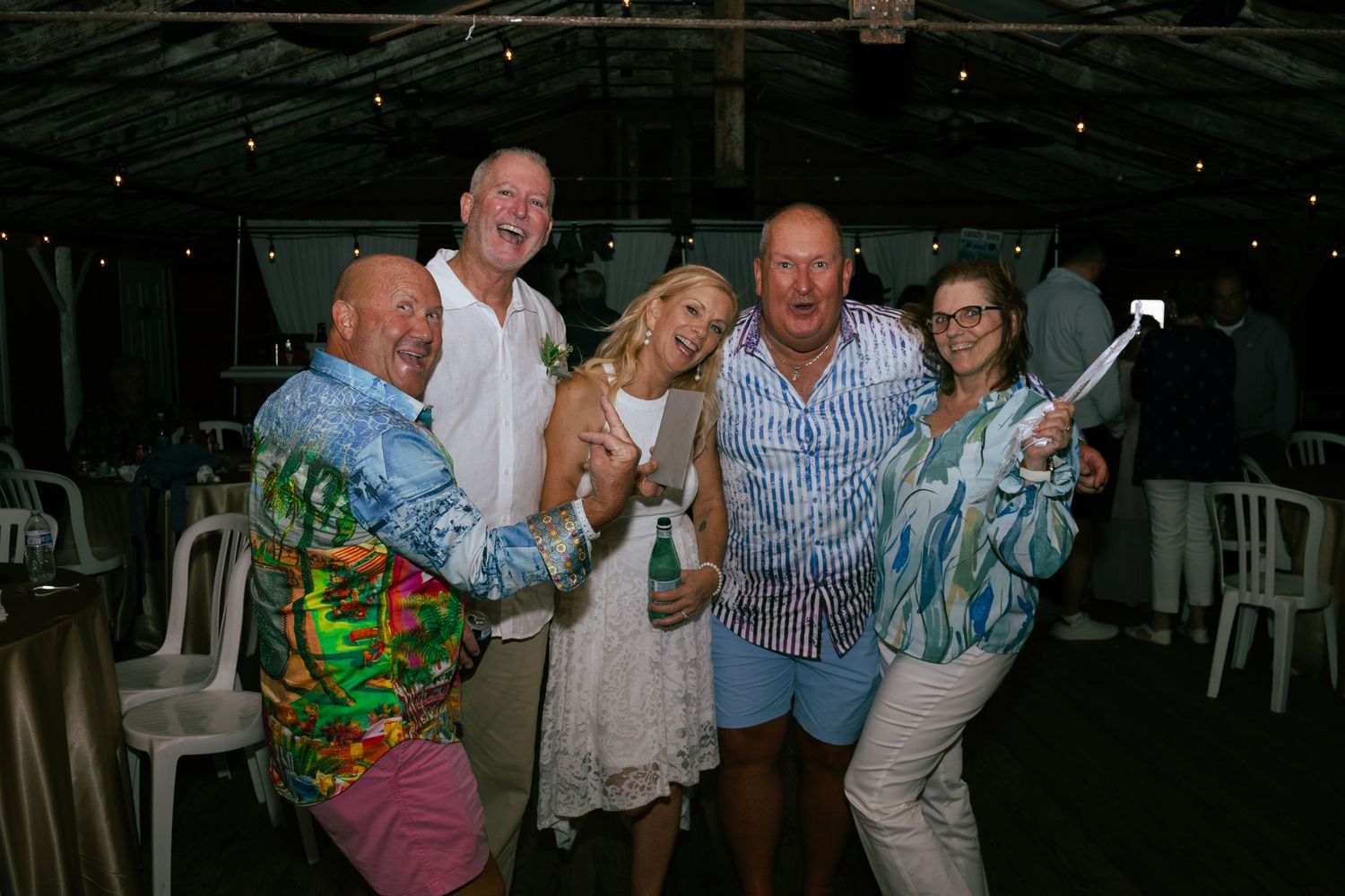 Joyful wedding guests celebrating with the bride at a tropical outdoor wedding reception.