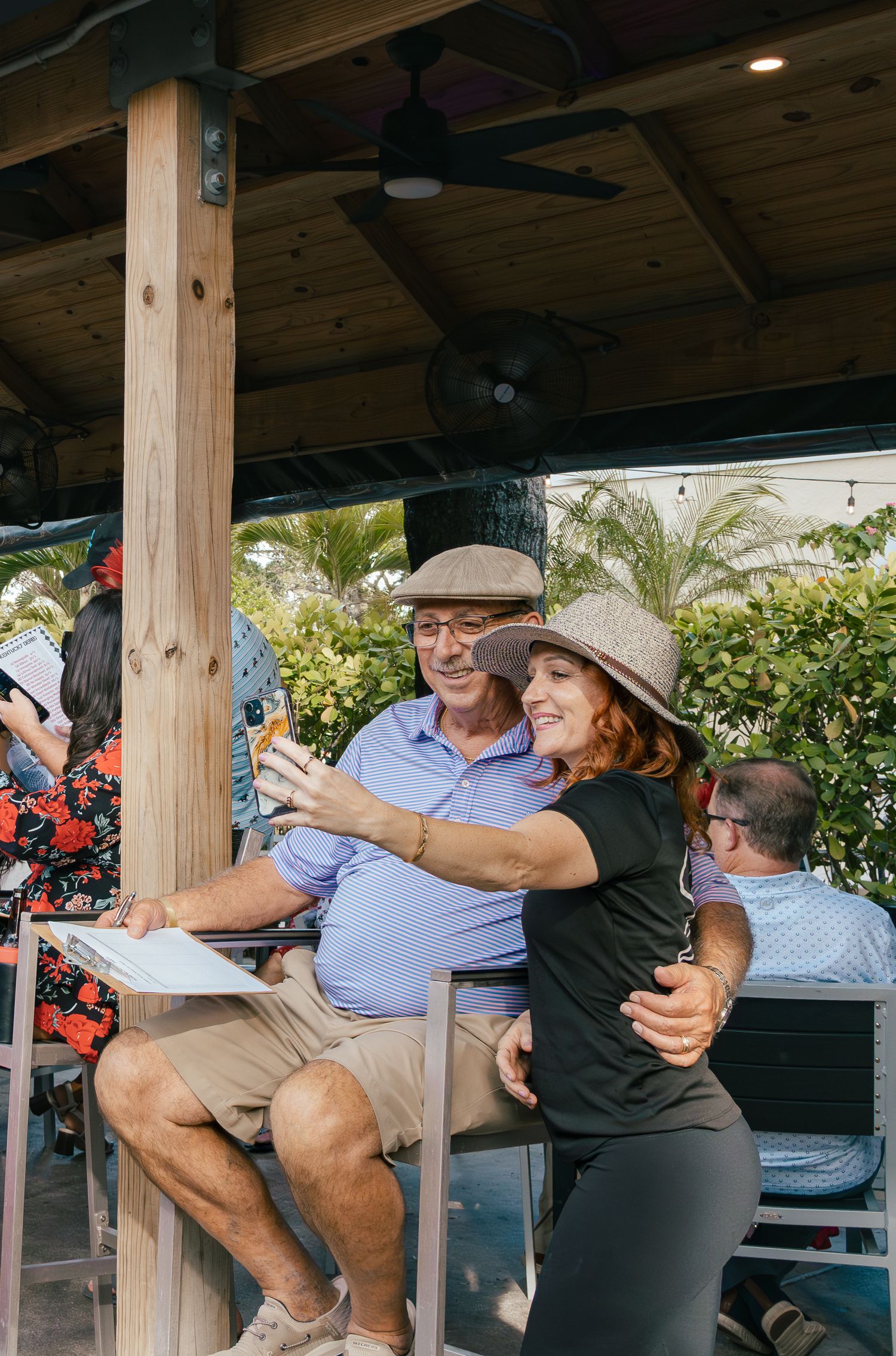 Man and woman take selfie together under covered outdoor patio area.