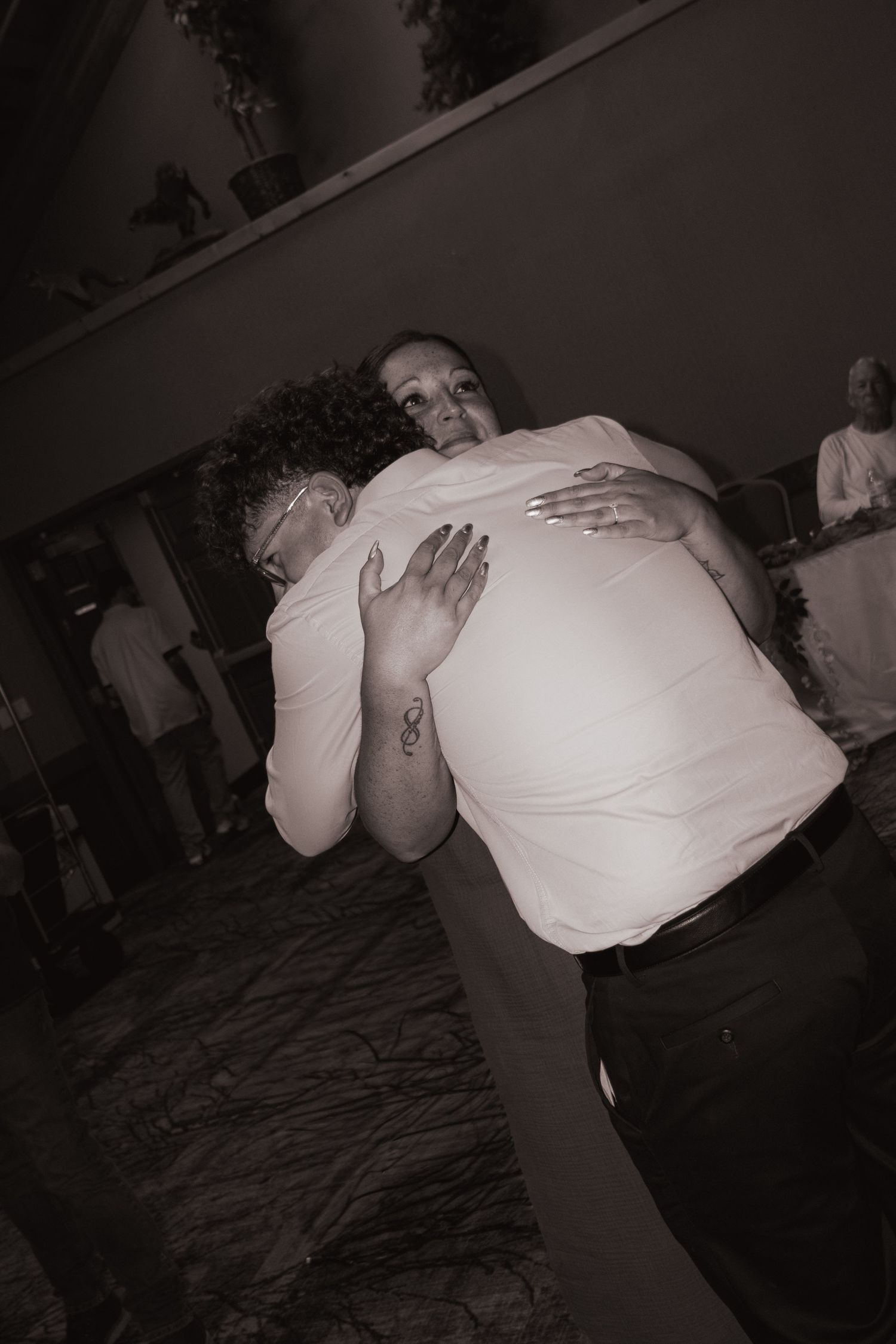 Black and white photo of couple sharing an emotional embrace on the wedding dance floor.