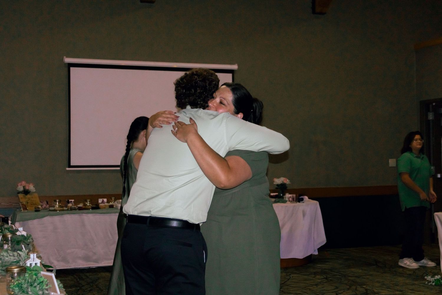 Two guests sharing a warm hug at an elegant wedding reception venue.