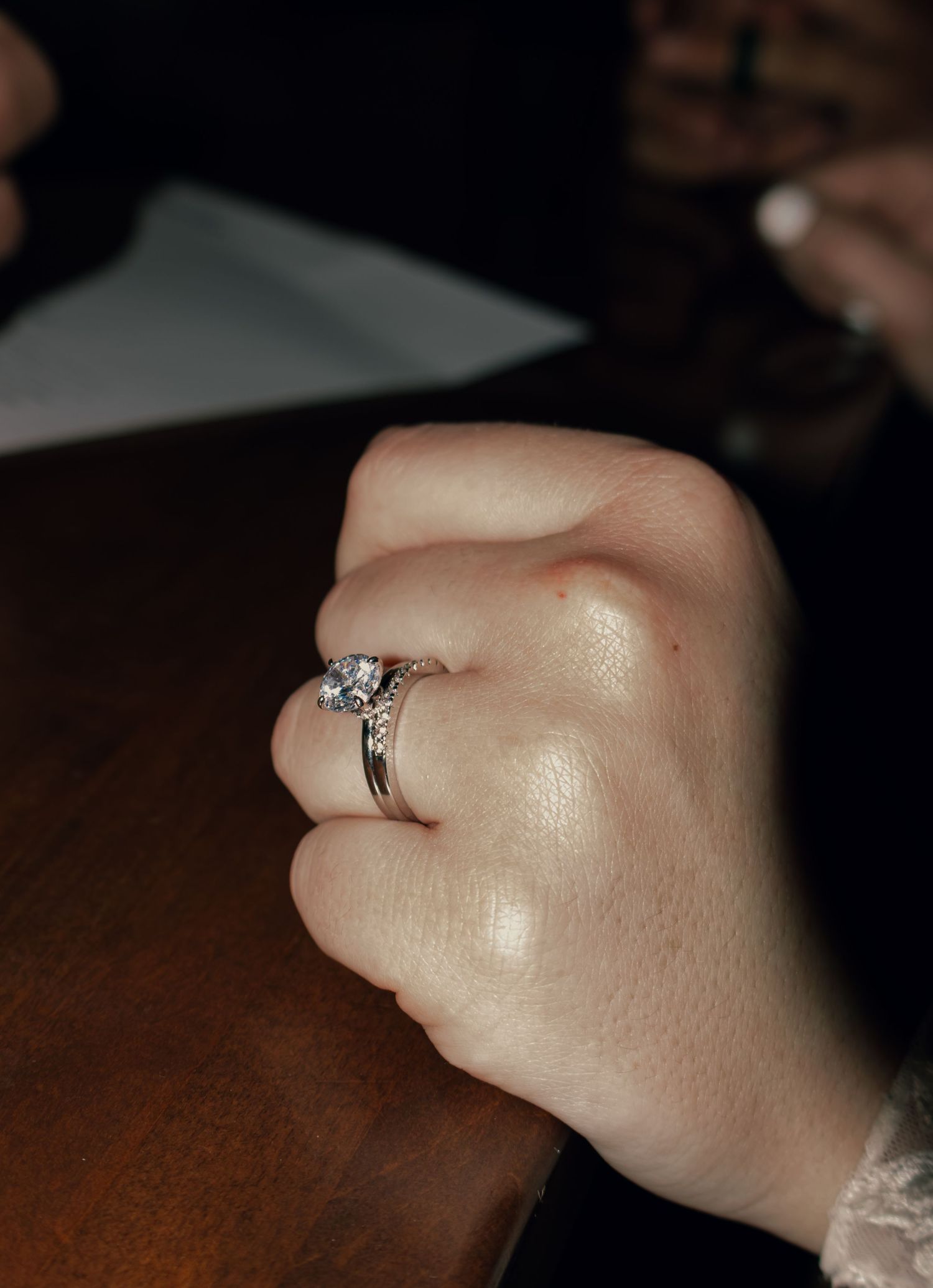 Close-up of bride's hand showing diamond solitaire engagement and wedding band rings.