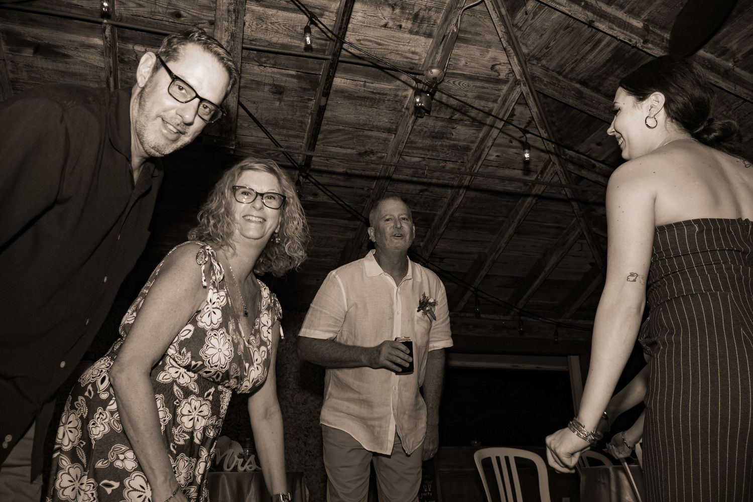 Sepia toned photo of guests socializing and dancing at evening reception.