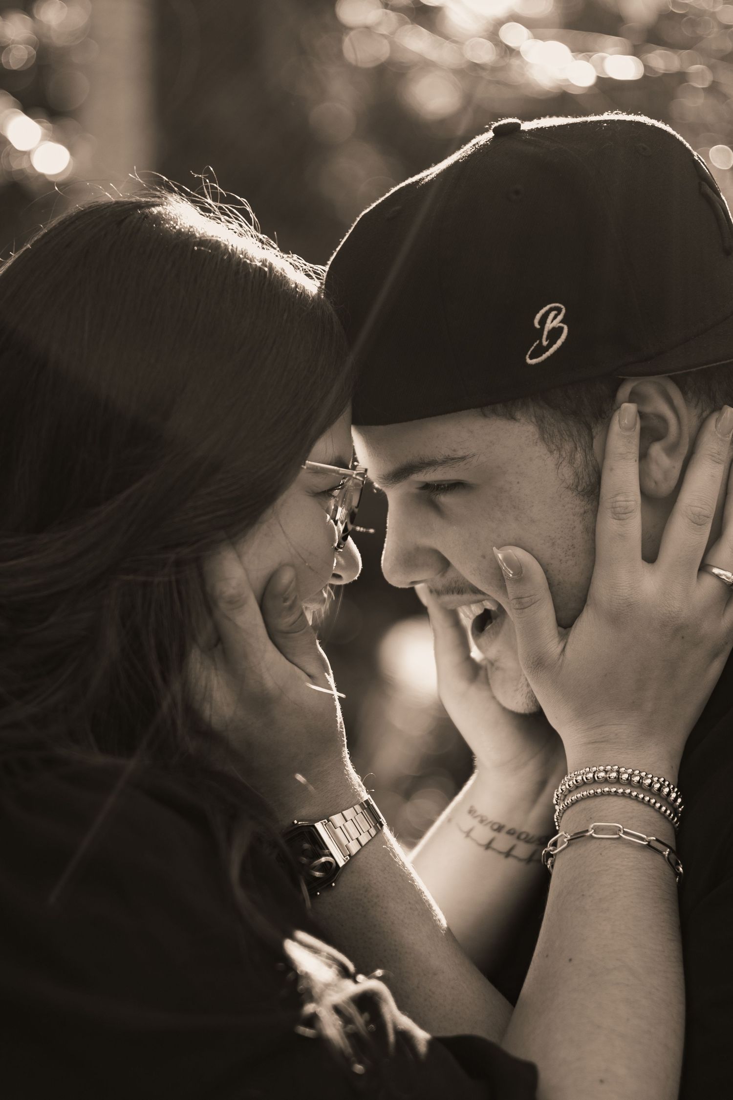 Black and white photo of a laughing couple sharing an intimate moment, woman cradling mans face in her hands.