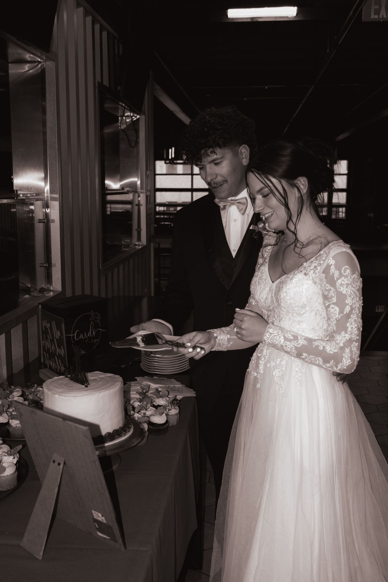 Black and white photo of bride and groom cutting their wedding cake together.