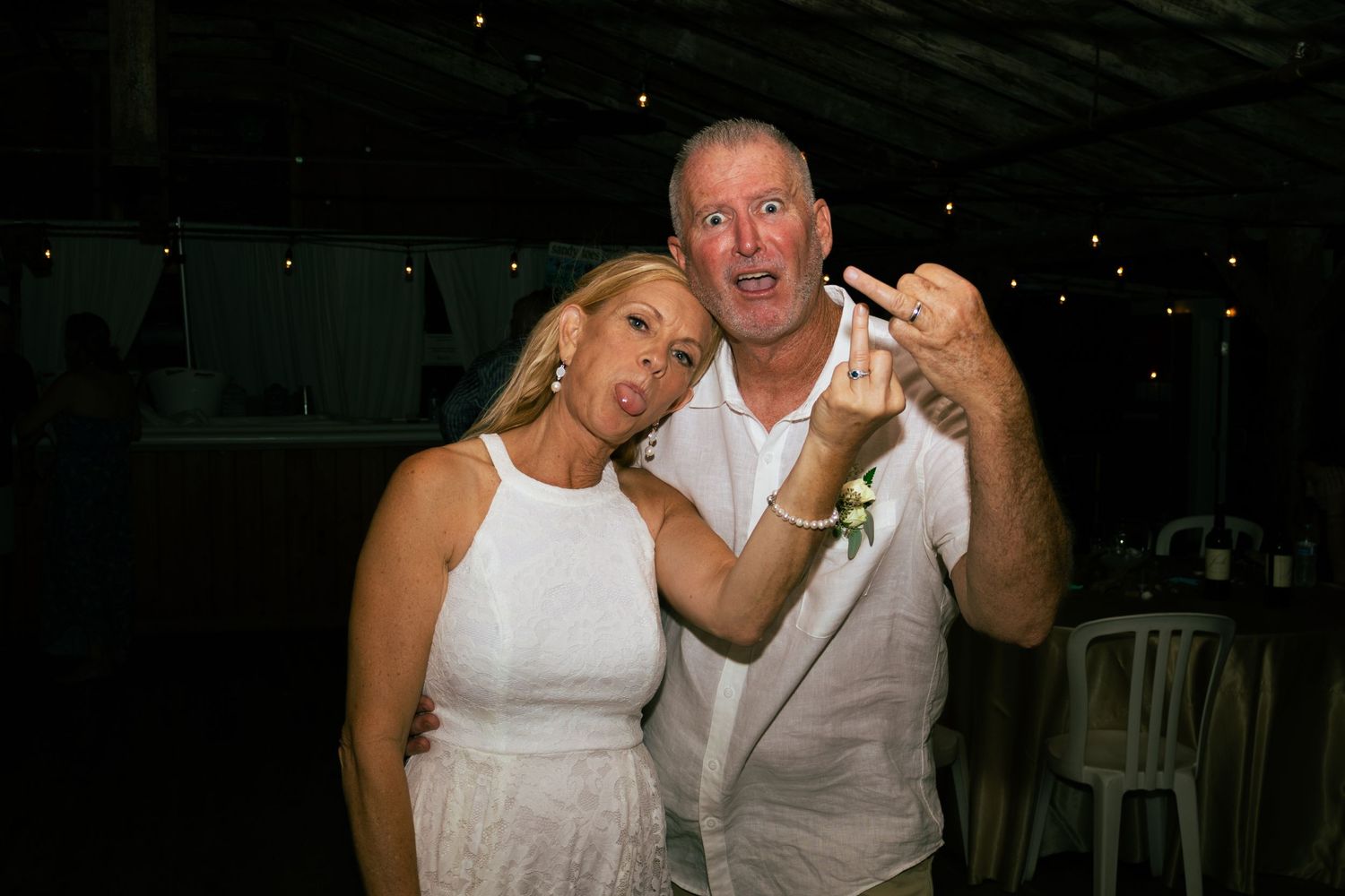 Bride and groom laughing and celebrating together at their outdoor tropical wedding reception.