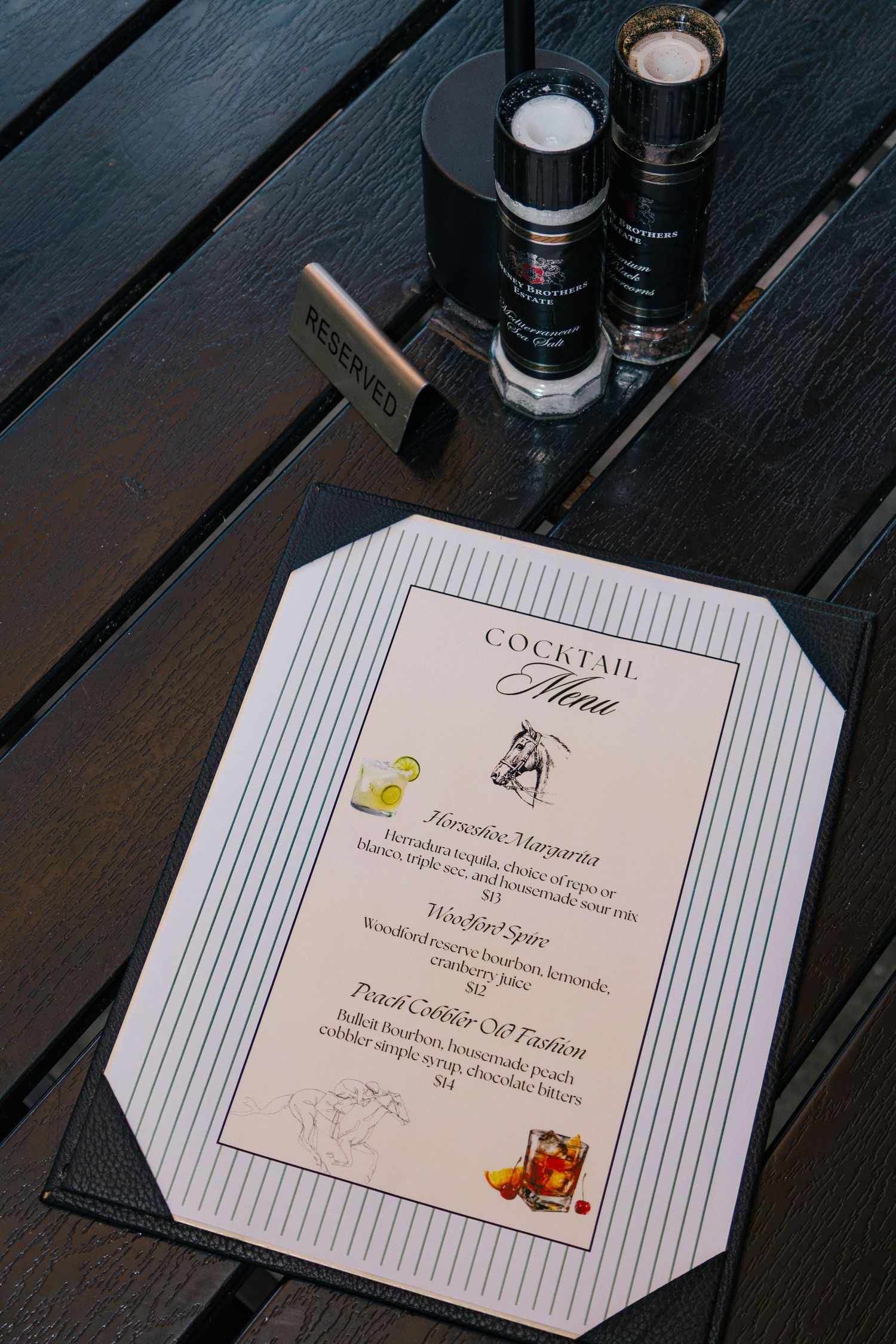 Cocktail menu on a dark wooden table featuring Margarita and Old Fashion drinks at a Kentucky Derby event.