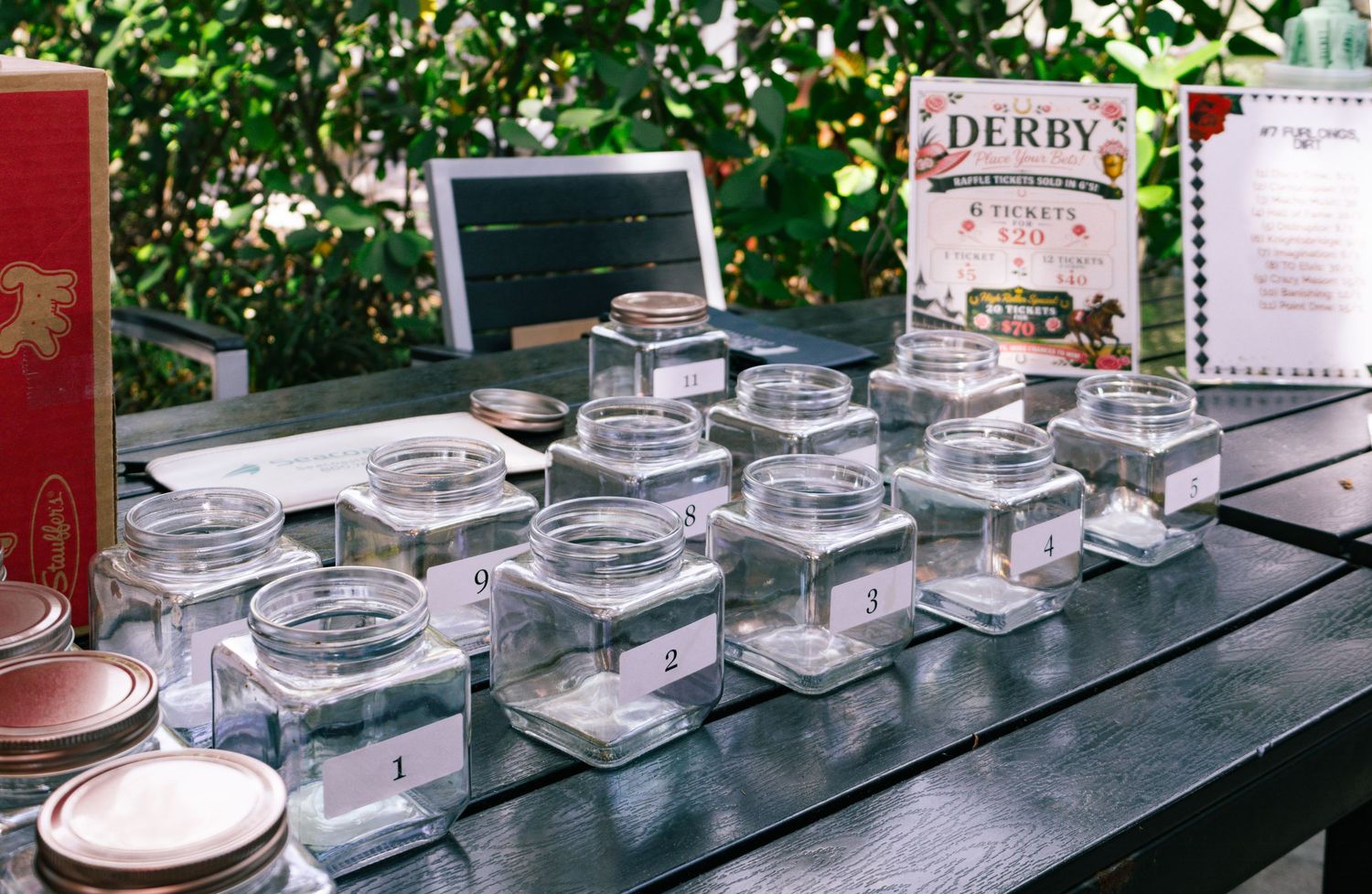 Numbered glass jars displayed on dark table with Kentucky Derby sign for a tasting event.