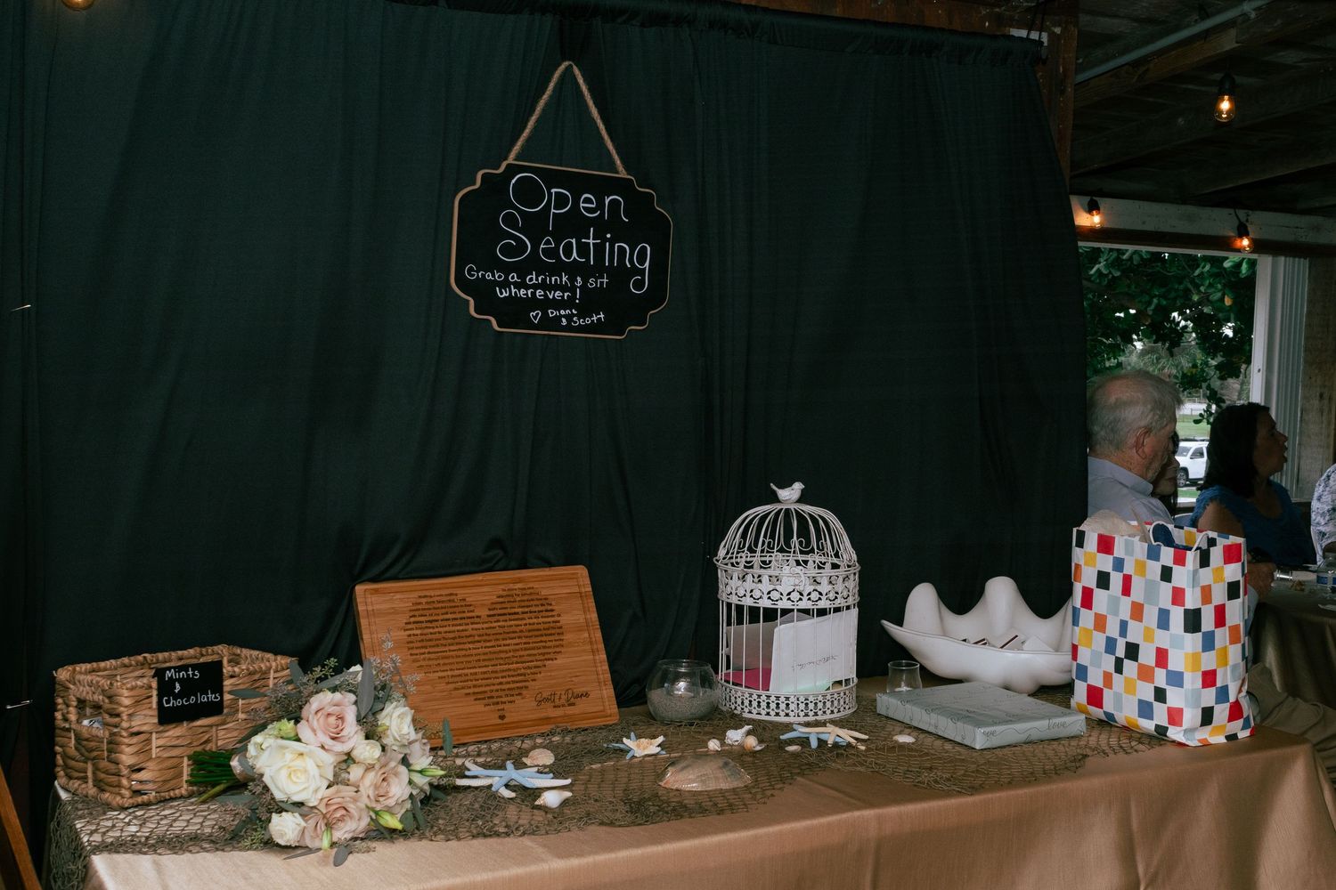 Wedding reception open seating table with white floral arrangement, birdcage, and guest book.