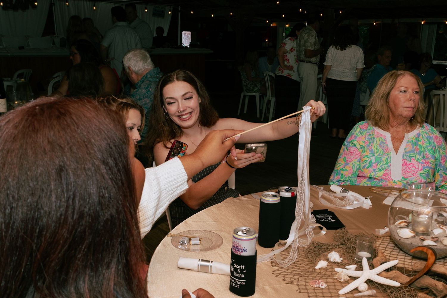 Wedding guest stretches silly putty at decorated reception table with starfish decor.