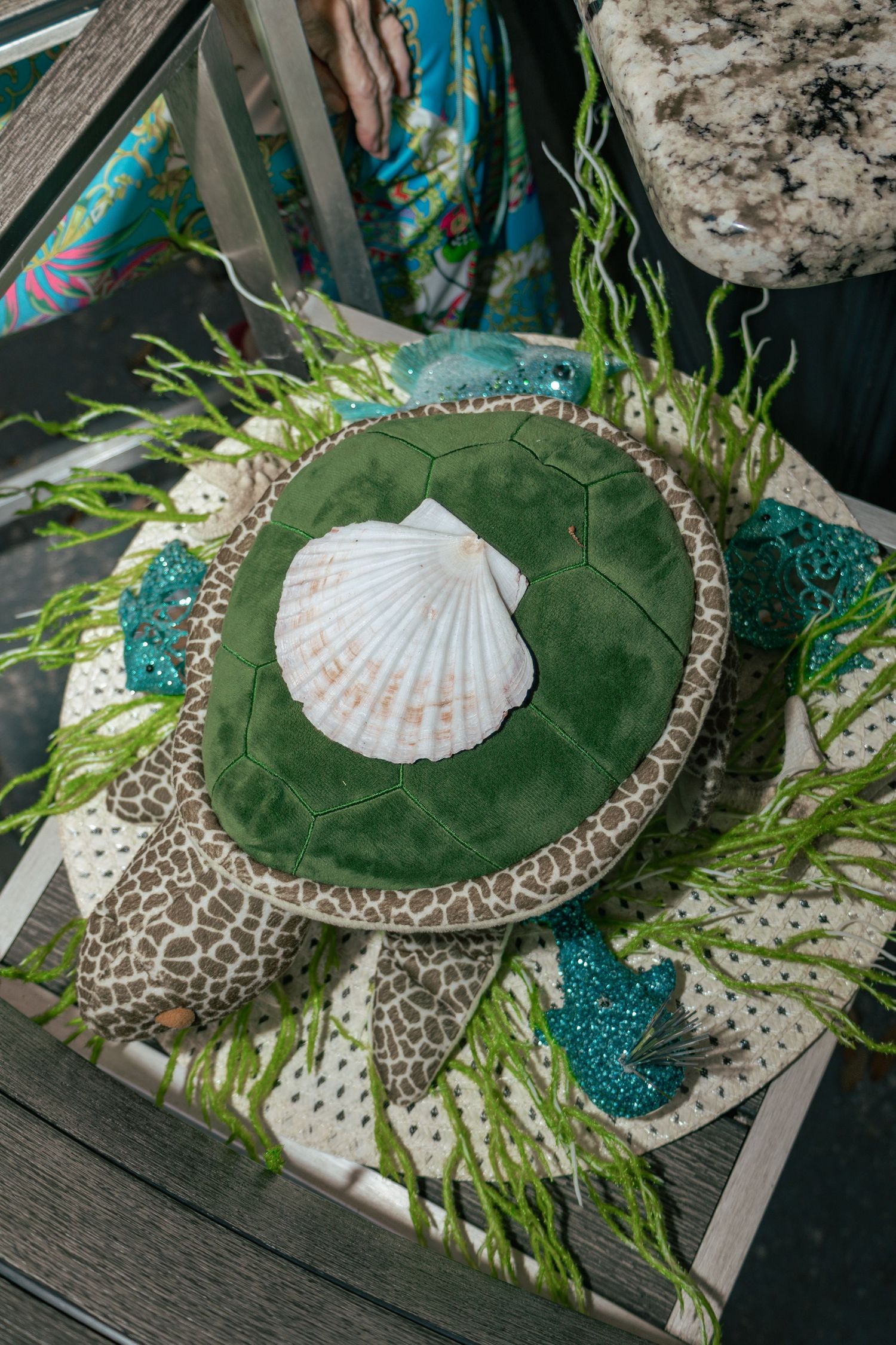 Decorative sea turtle centerpiece with seashell, green seaweed, and teal seahorses on display table.