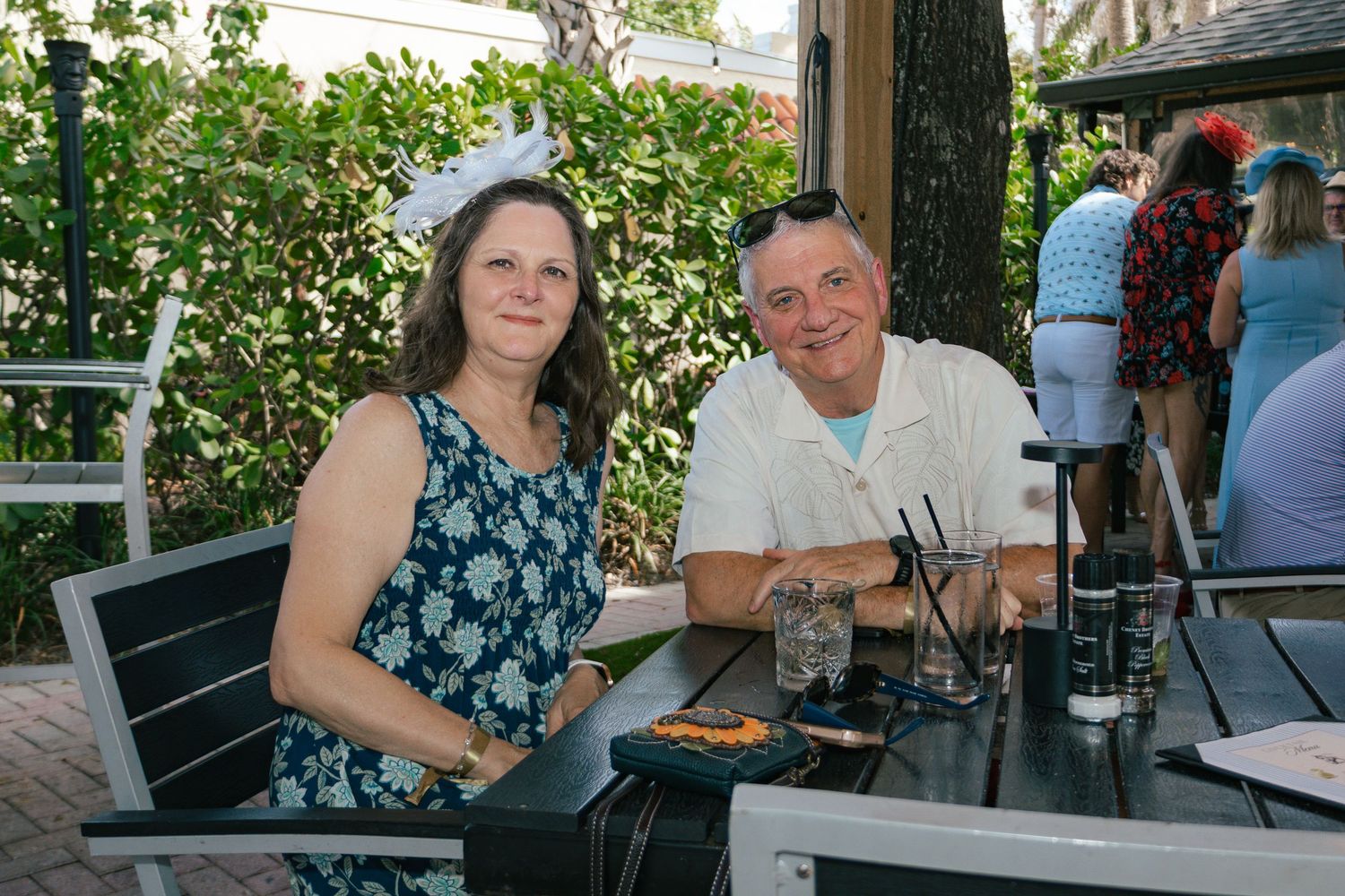 Couple sitting at outdoor patio table at a Kentucky Derby themed party event.