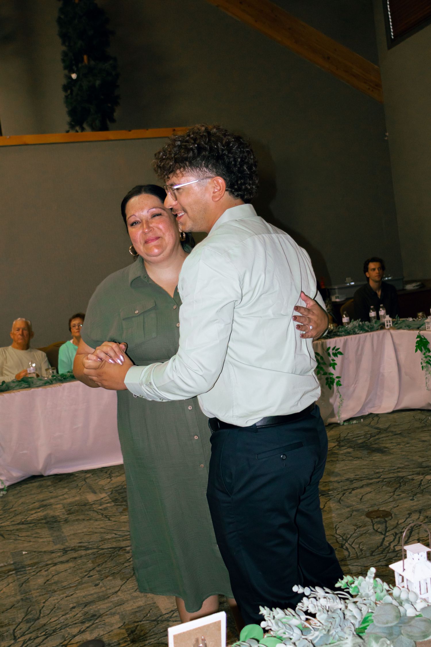 Couple shares a romantic dance at a wedding reception in a decorated banquet hall.