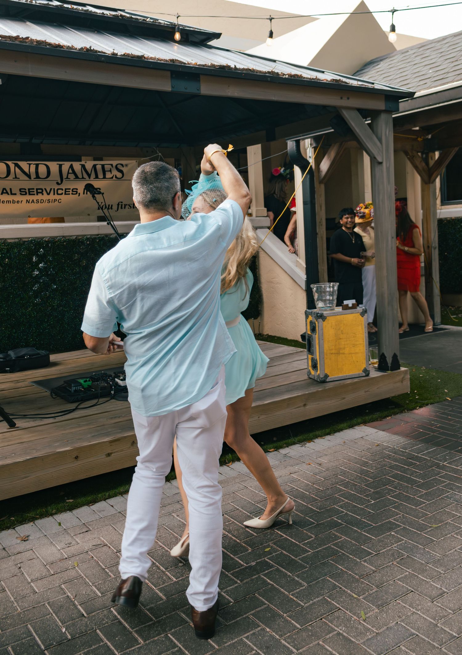 Couple dancing outdoors near stage with Bond James Financial Services banner in background.