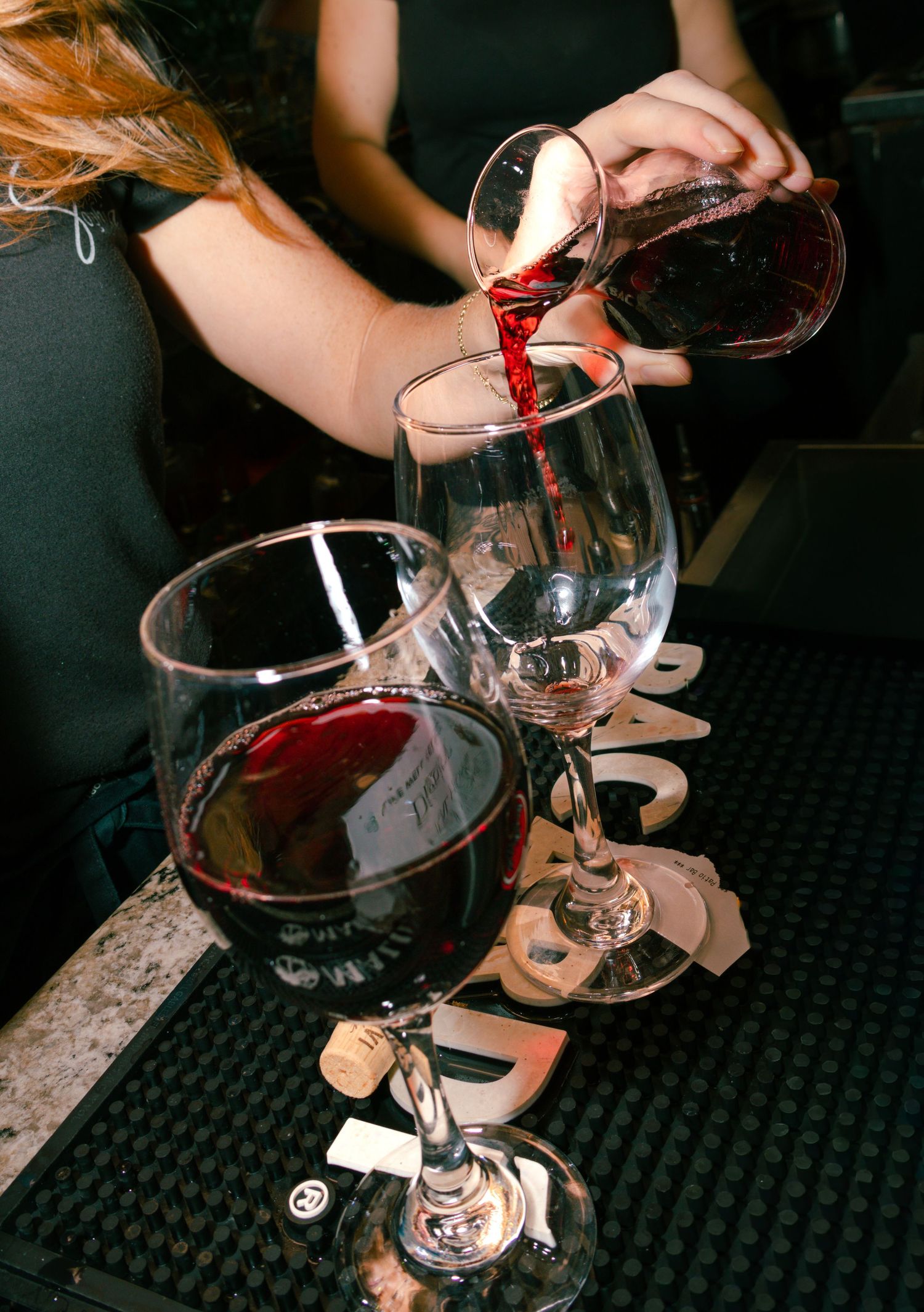 Bartender pouring red wine into elegant crystal glasses at an upscale event bar.