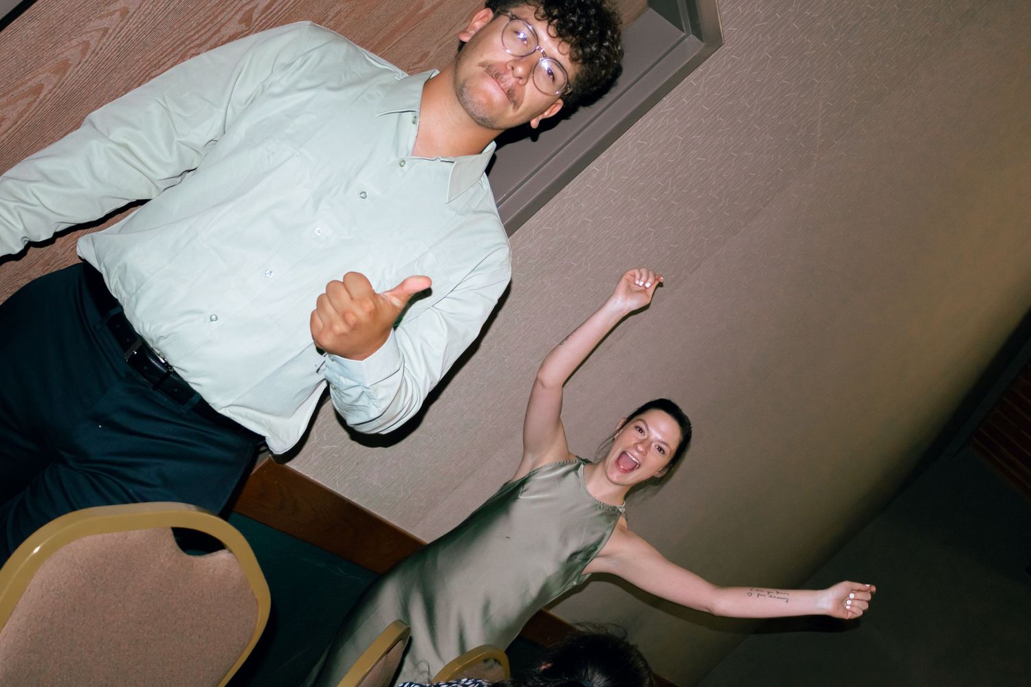 Two men celebrating at wedding reception with thumbs up and dance moves.