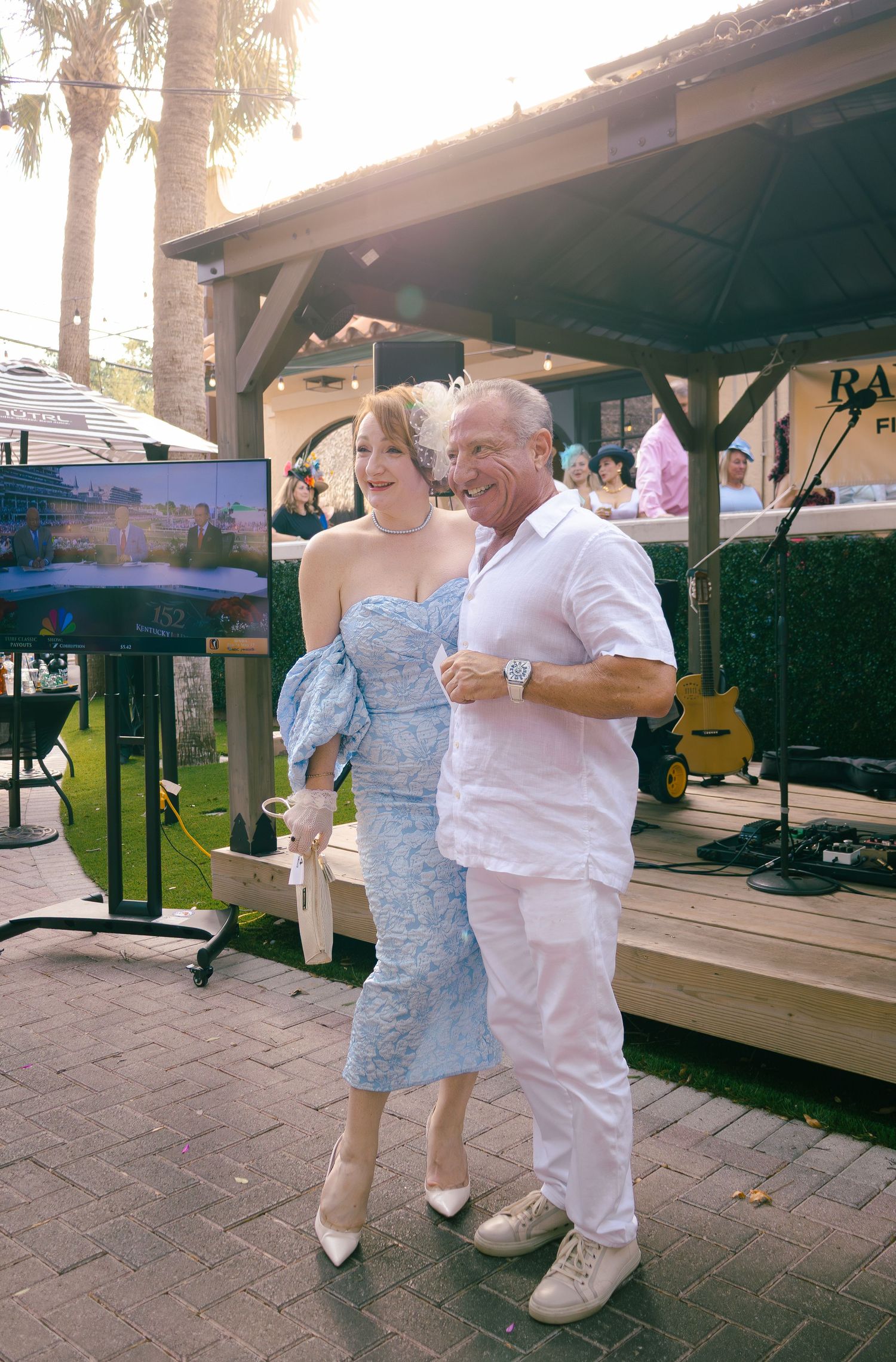 Couple posing together in elegant attire at outdoor Raymond James financial event.