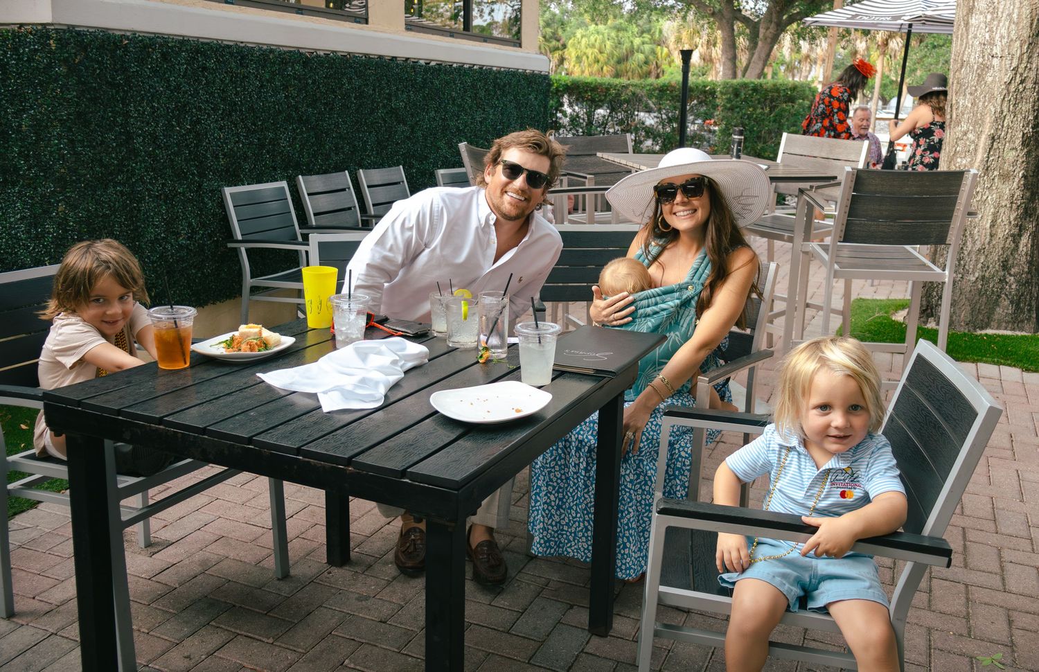 Young family with two toddlers enjoys outdoor dining at Kentucky Derby themed party event.