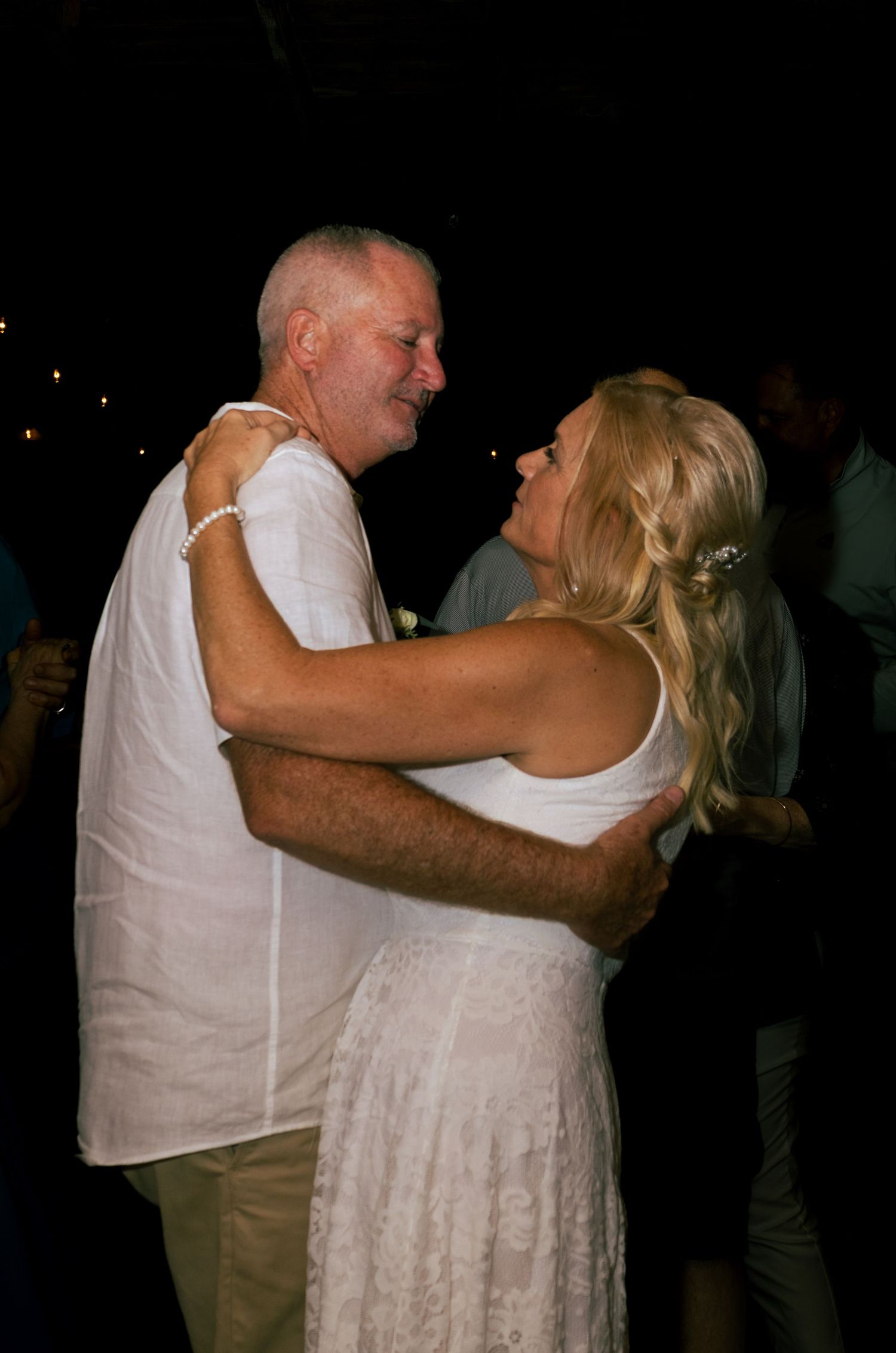 Newlyweds share a romantic slow dance embrace at their outdoor evening wedding reception.