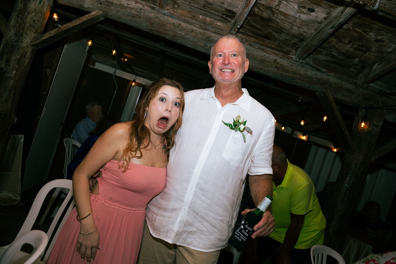 Woman making surprised face posing with man wearing boutonniere at wedding.