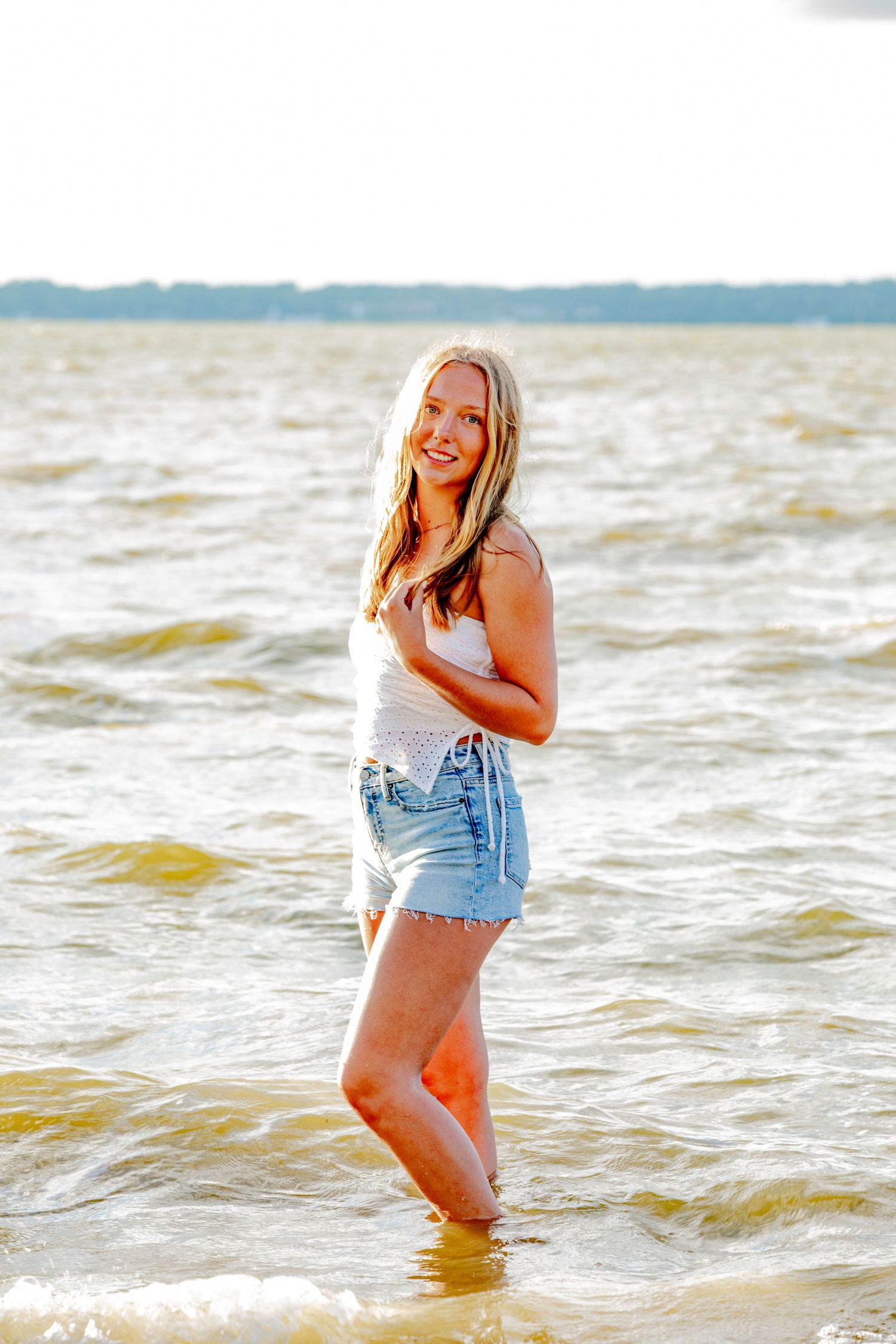 Playful lifestyle photos of someone enjoying waves at the beach in casual summer attire.