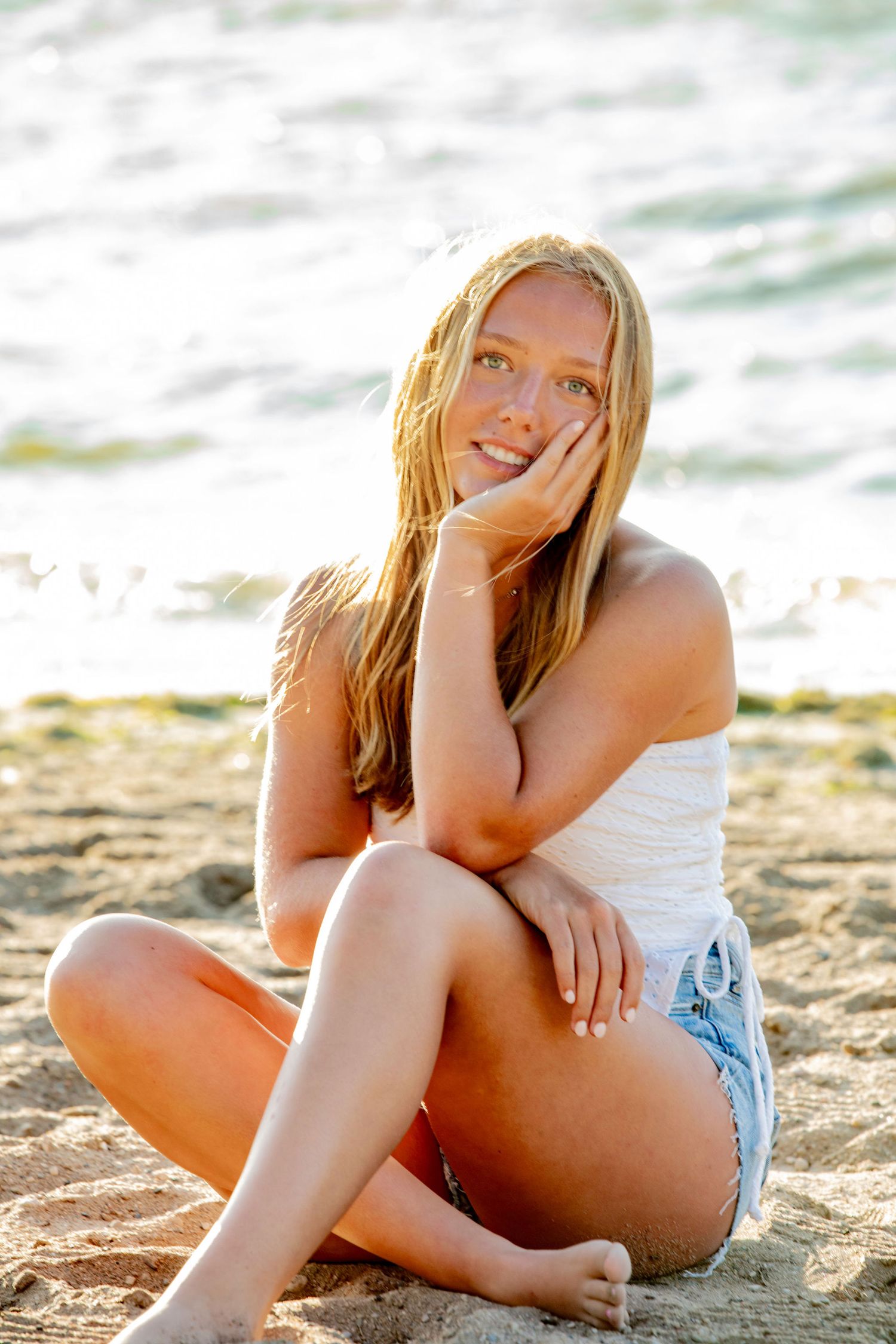 Relaxed summer beach portraits showing someone sitting on sandy shore at sunset.