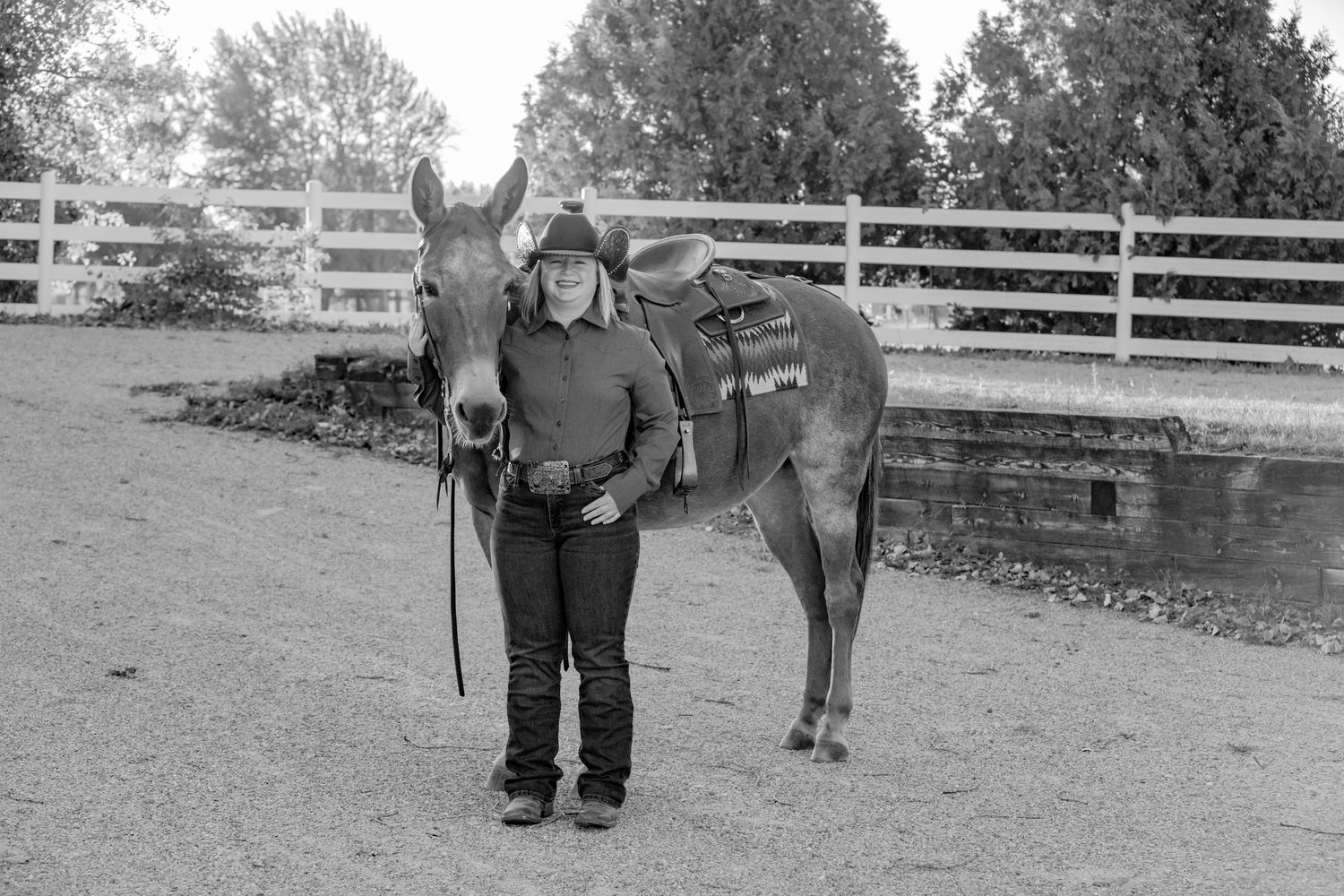 Black and white photo of horse and handler in a rustic outdoor setting.