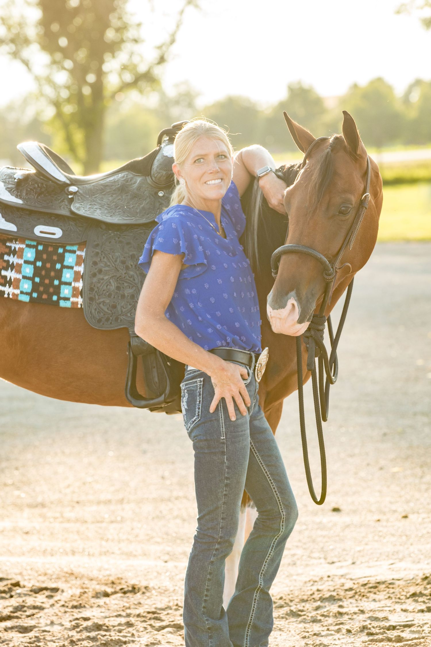 Golden sunlight illuminates horse and rider sharing a joyful moment at a barn.