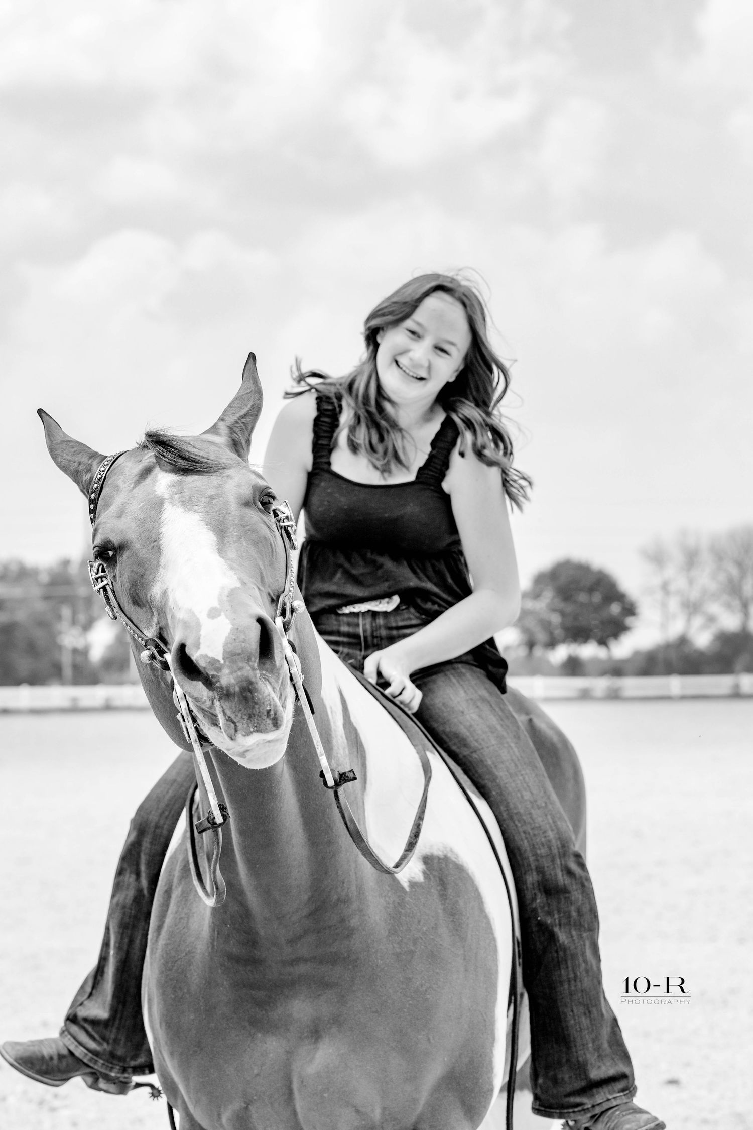 A horse and rider share a playful moment in black and white photography.