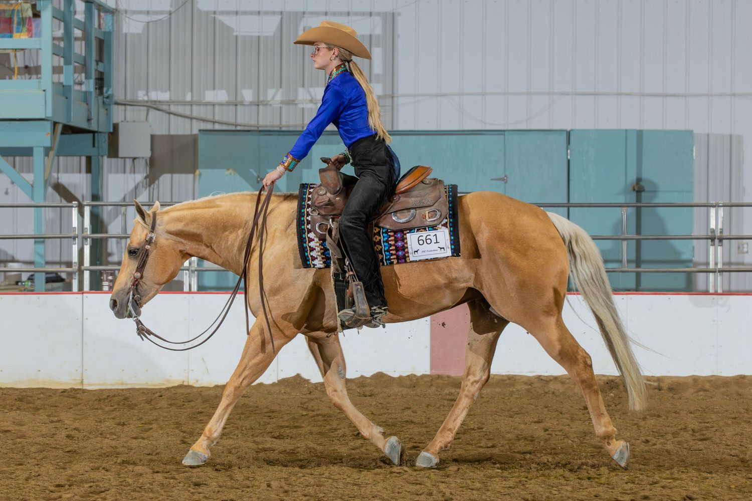 Equestrians practicing horseback riding techniques in an indoor arena setting.