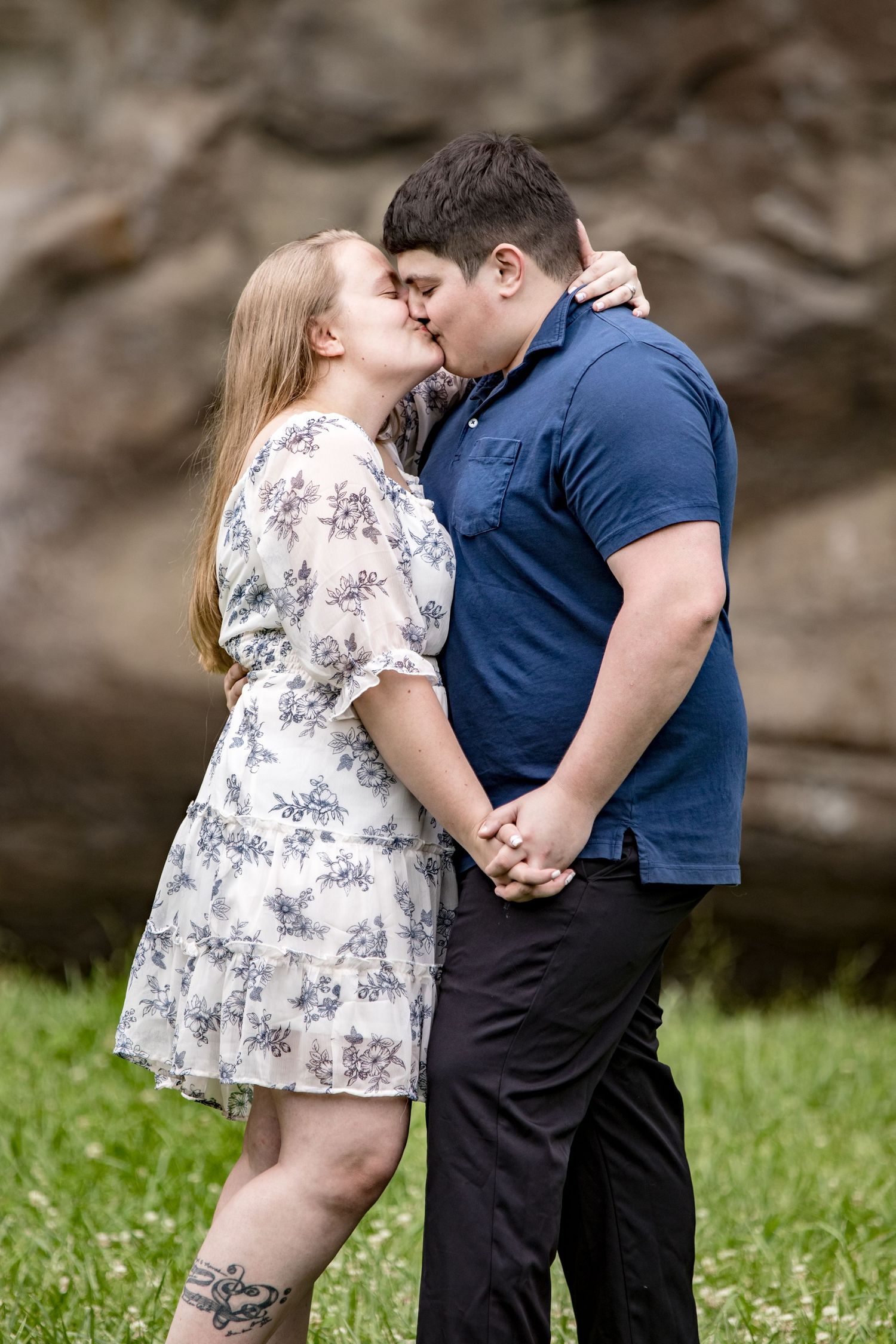 A romantic moment shared between a couple against a dramatic rock wall background.