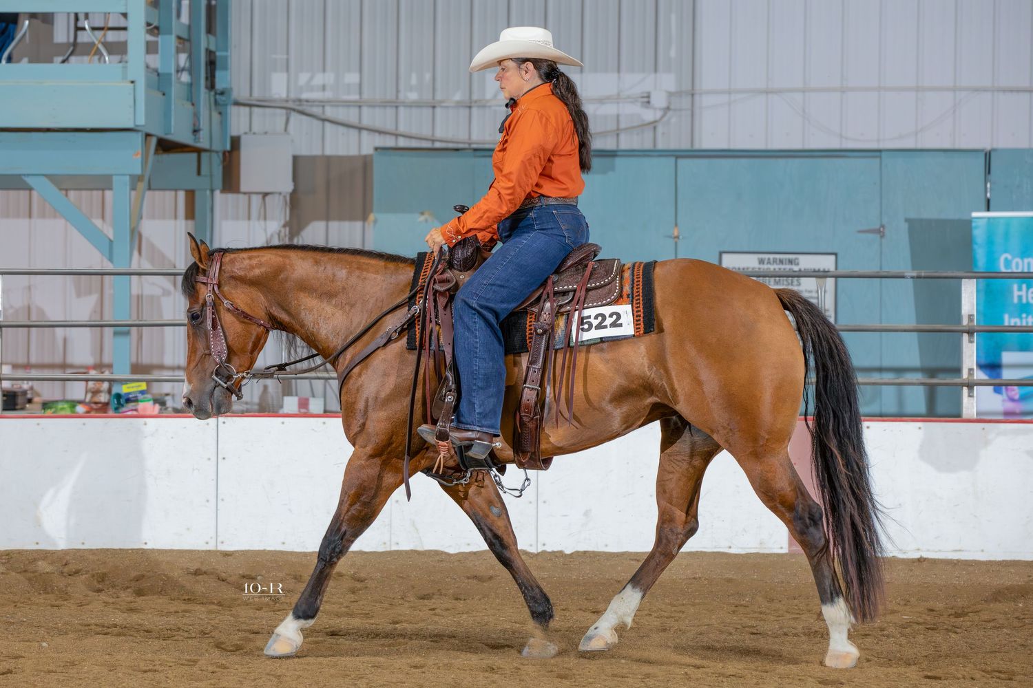 Western horse competition in an indoor arena with blue walls.