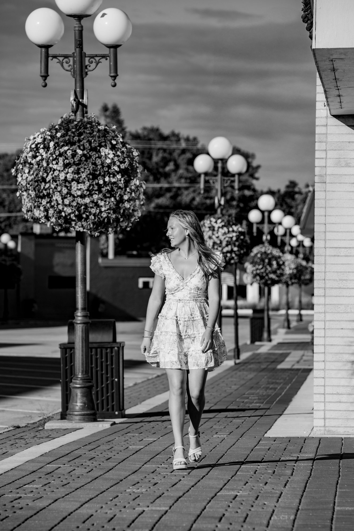 Black and white sequence showing someone walking along a boardwalk with decorative lampposts.