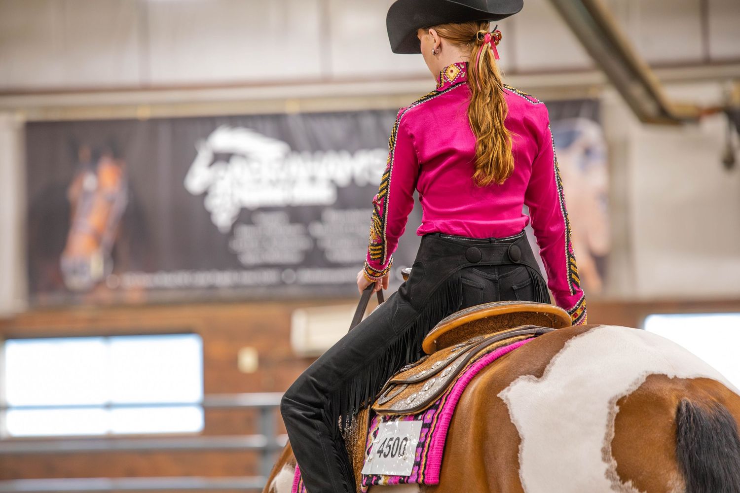 Horse and rider competing in western riding event inside arena.