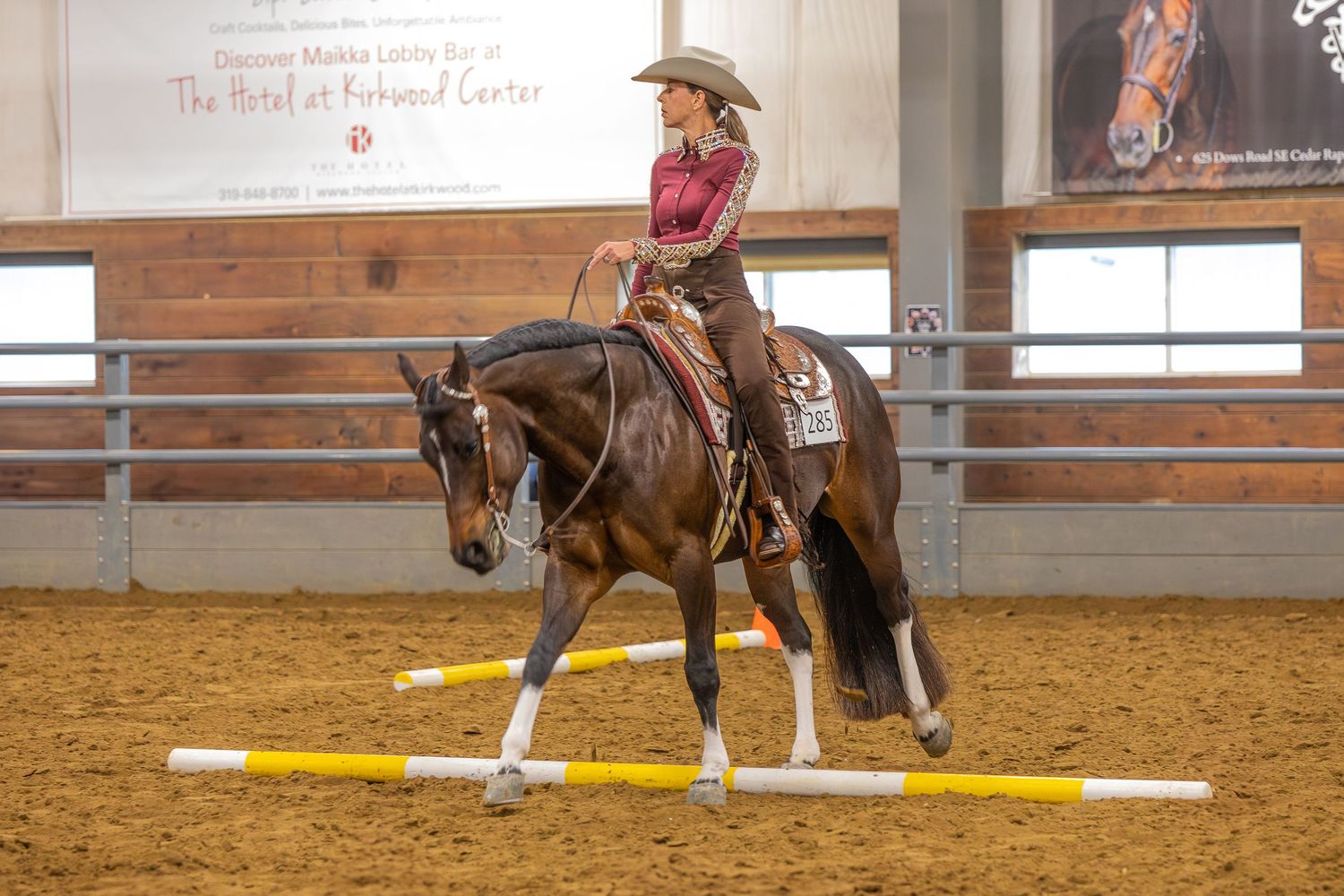 Horse and rider demonstrating dressage movements in an indoor competition arena.