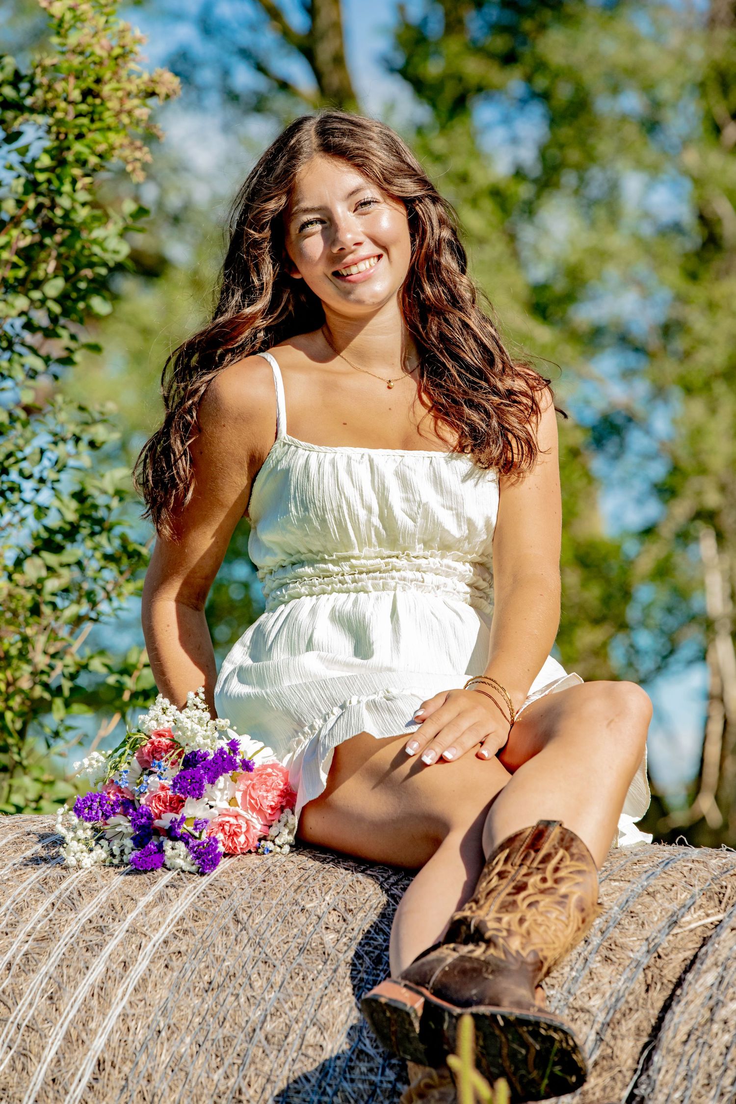White summer dress against natural stone backdrop with colorful wildflowers in sunlit outdoor setting.