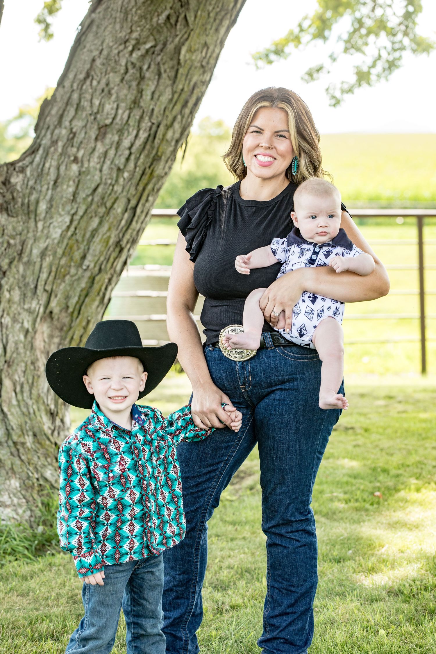 Family portrait outdoors with toddler and young child in western wear.