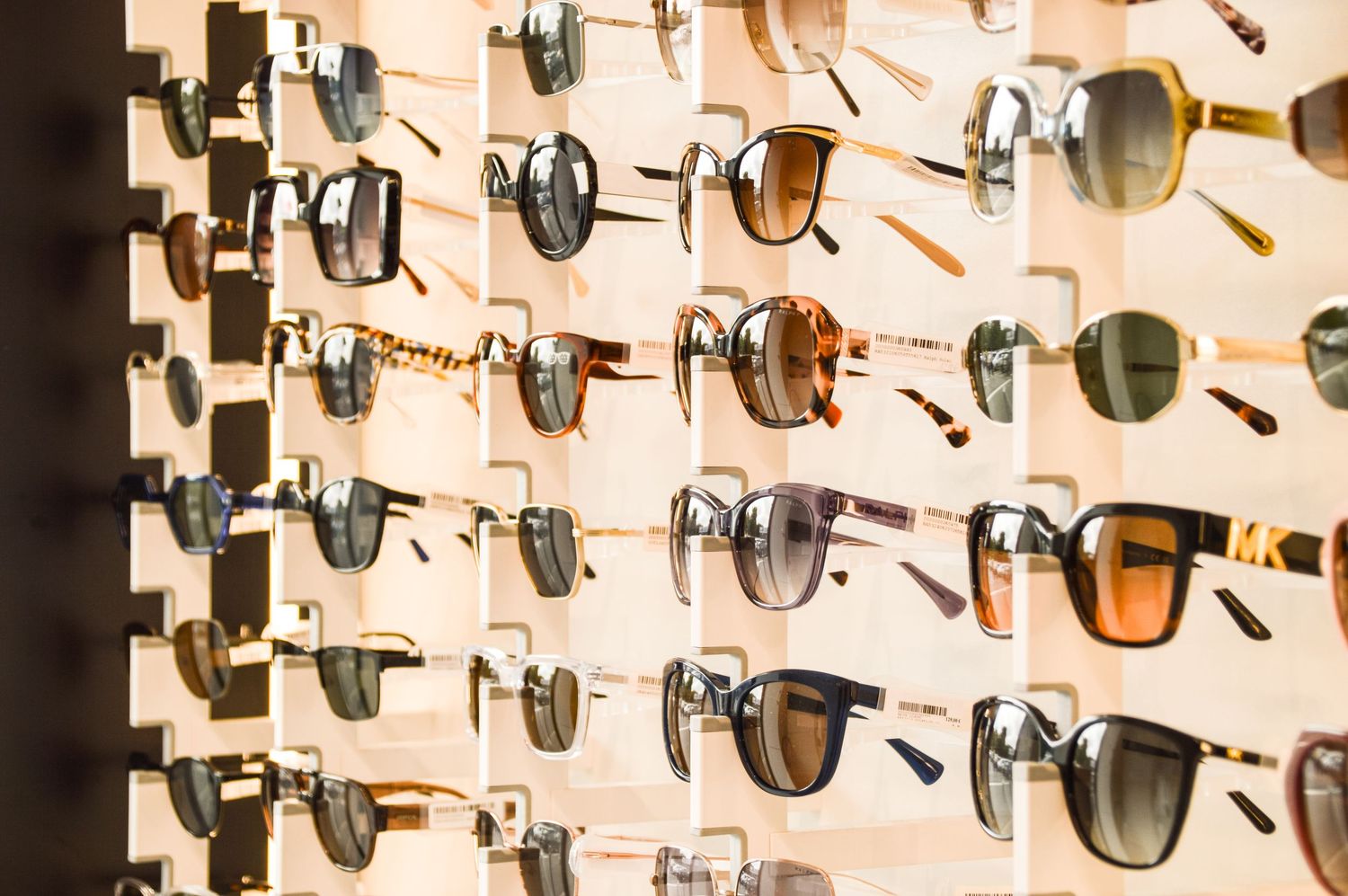 Collection of luxury sunglasses arranged in neat rows on retail display wall.