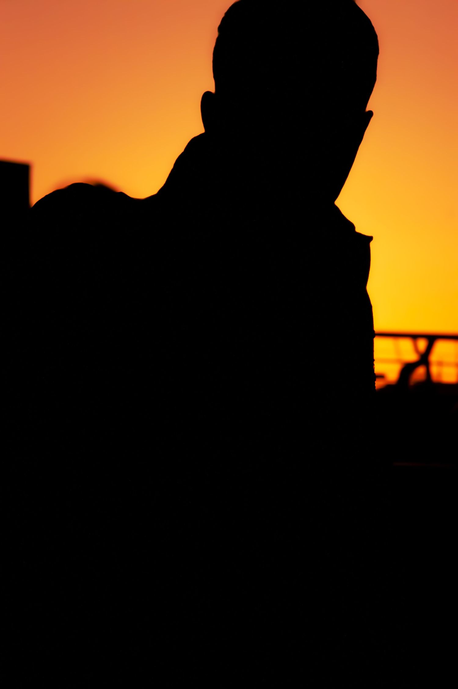 Silhouette of a person against vibrant orange and yellow sunset sky creating dramatic contrast.