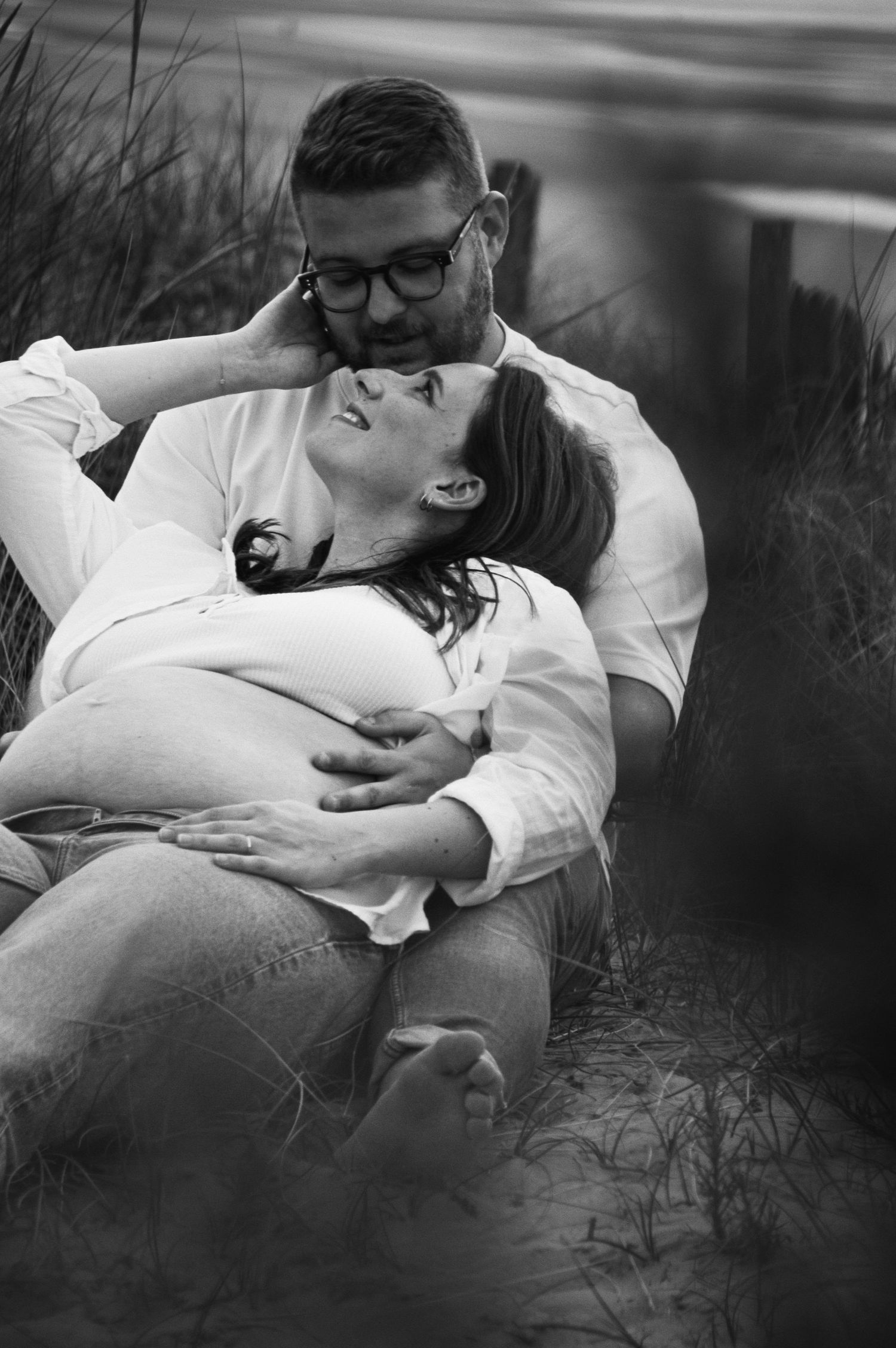 A romantic black and white photo series captures intimate moments between a couple on the beach.