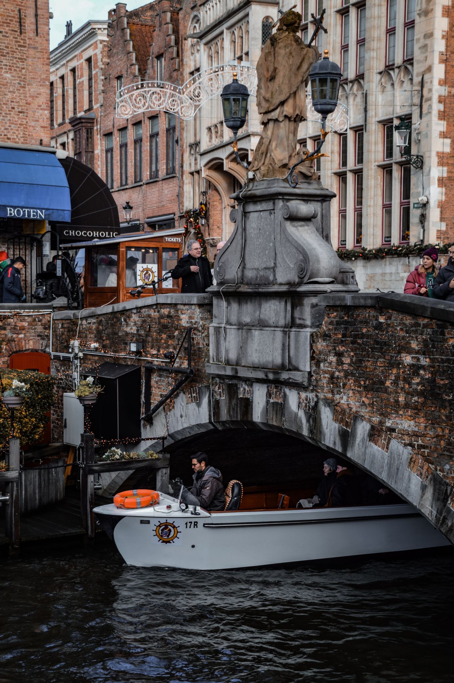 Historic canal in Bruges with traditional boats and brick buildings along the waterway.
