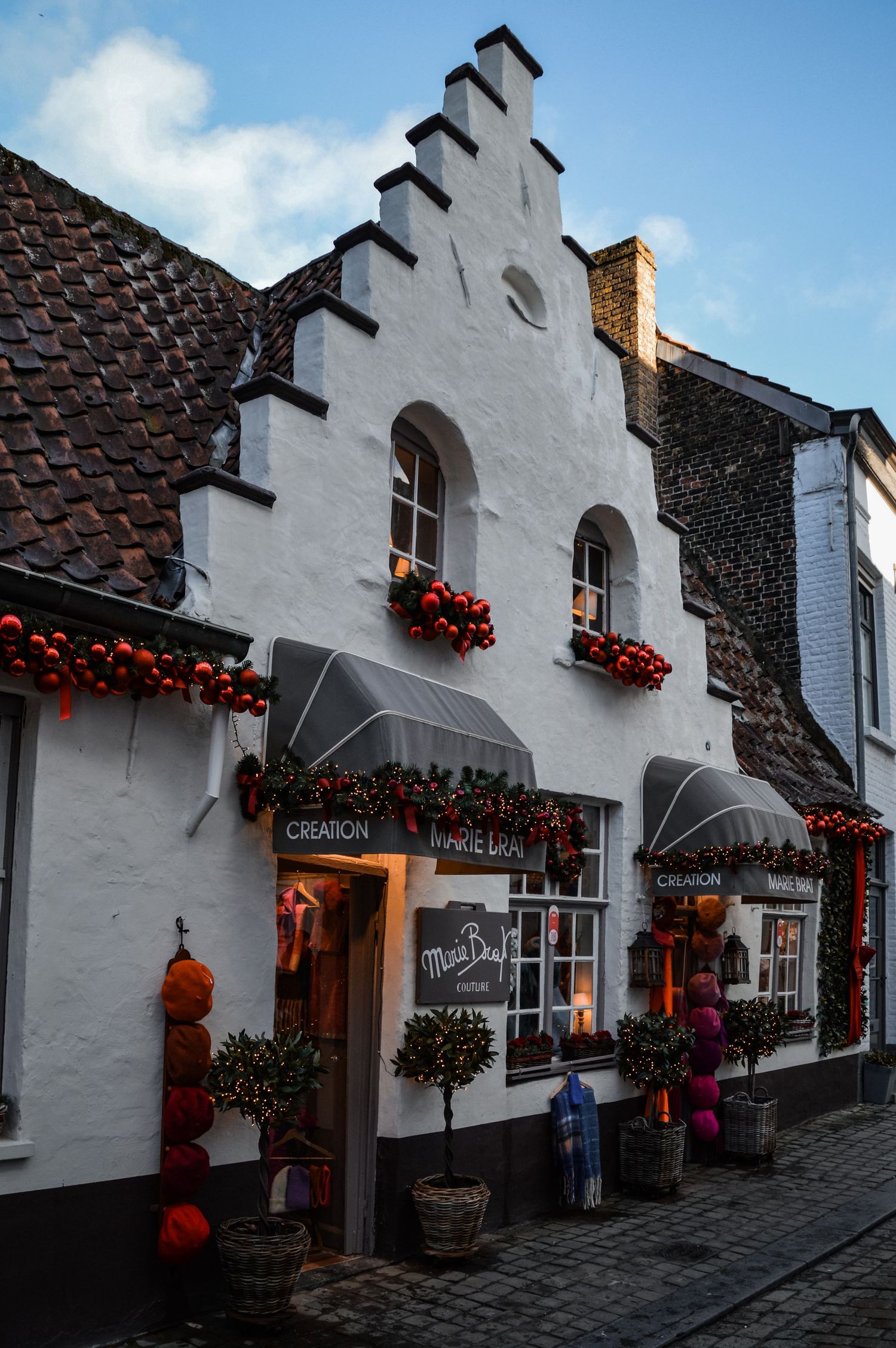 White historic buildings with red flowers in window boxes along a charming European street.