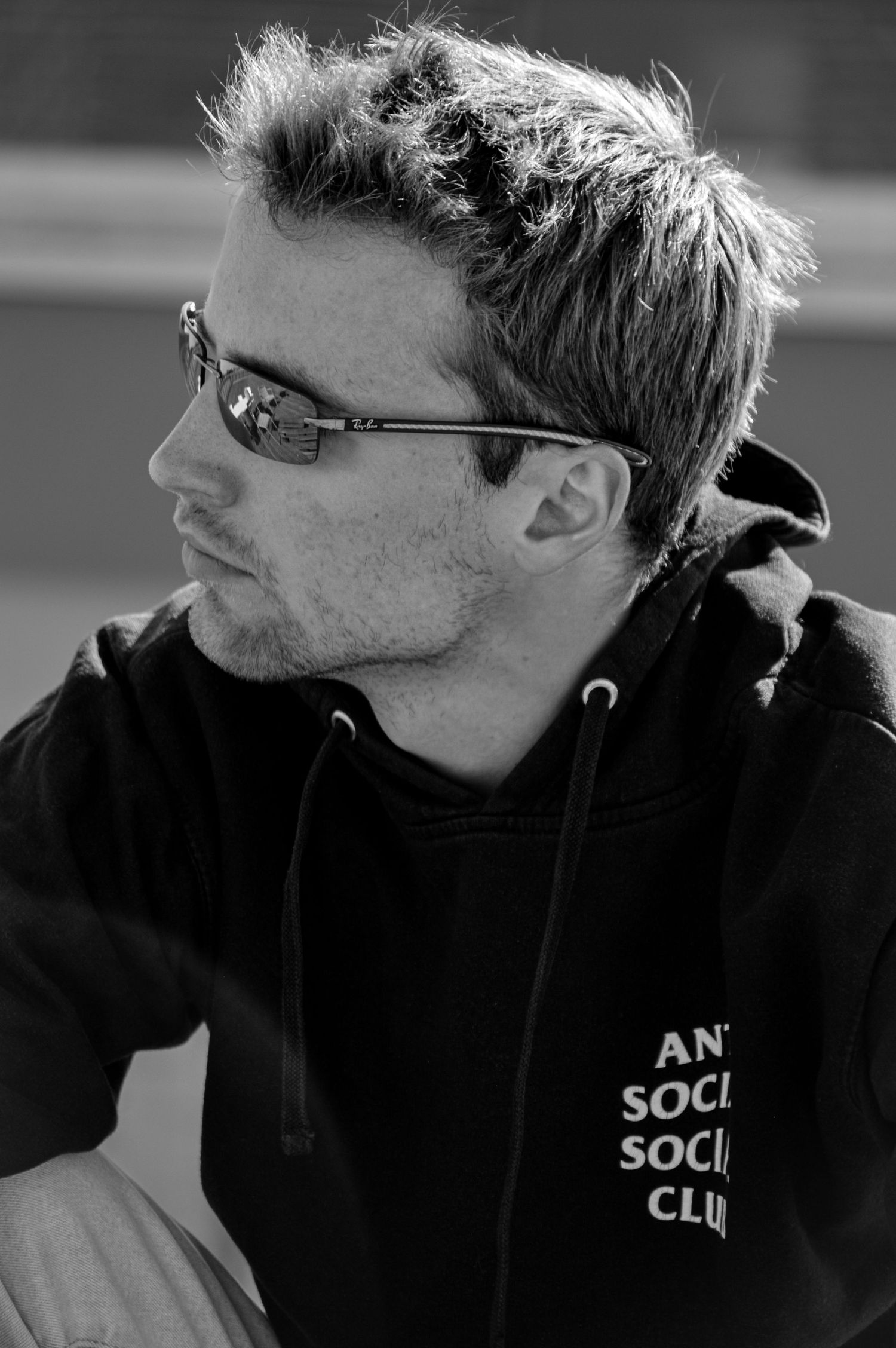 Side profile of person wearing black hoodie and glasses in monochrome.