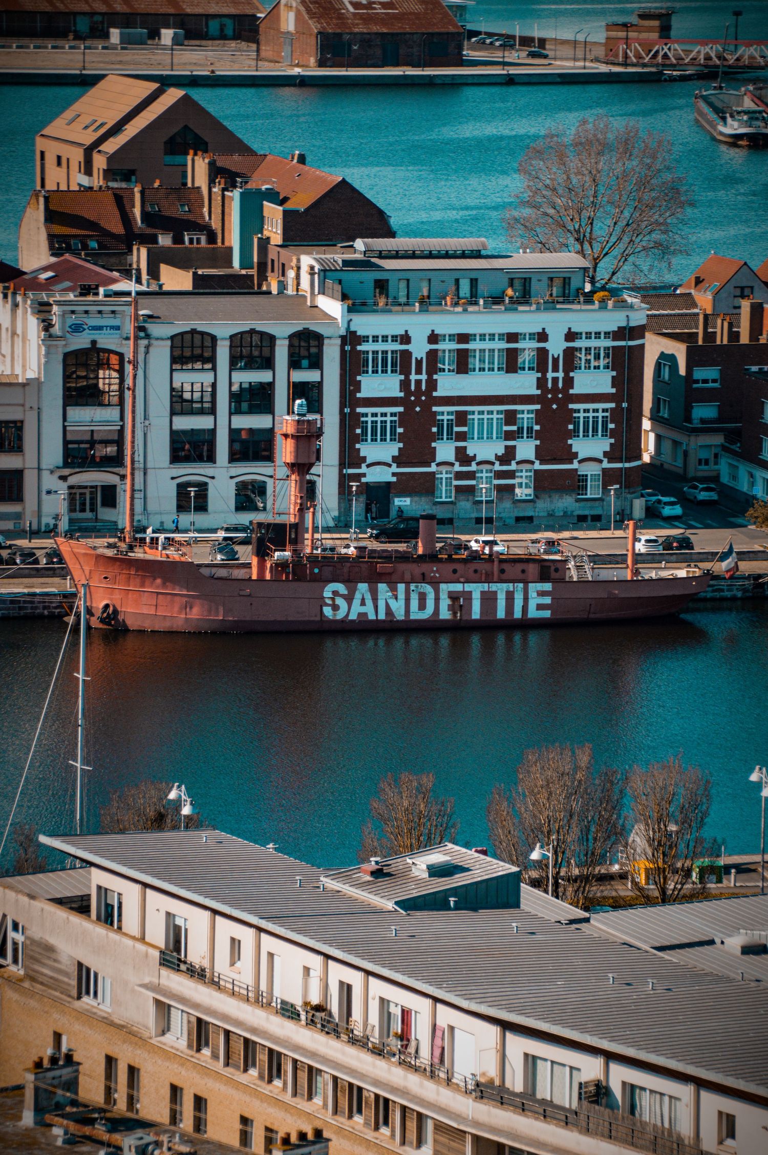 Waterfront view of buildings and boats with 'Sandettie' vessel visible in harbor.