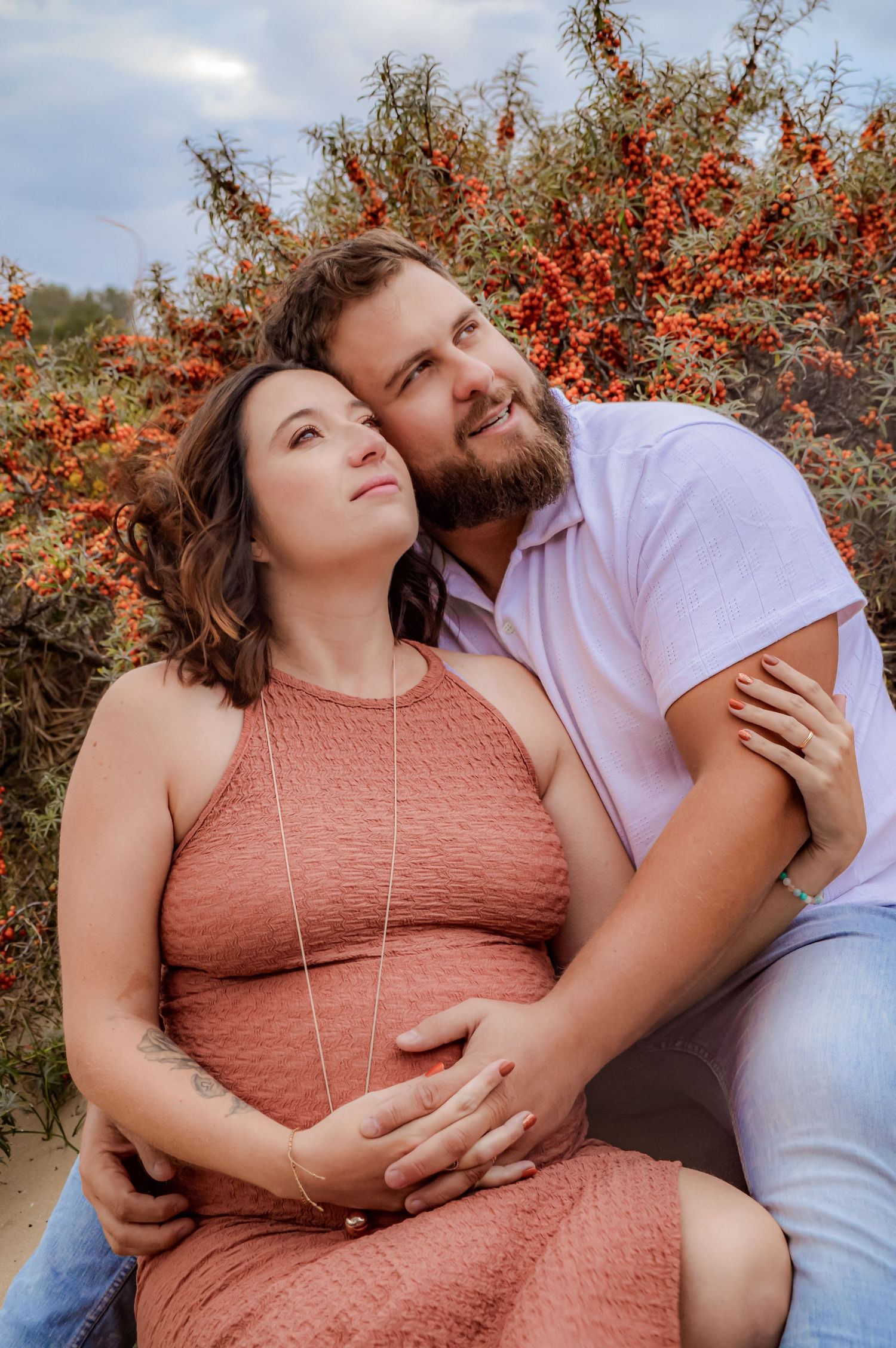 Couple in casual attire sharing intimate moments near flowering bushes.